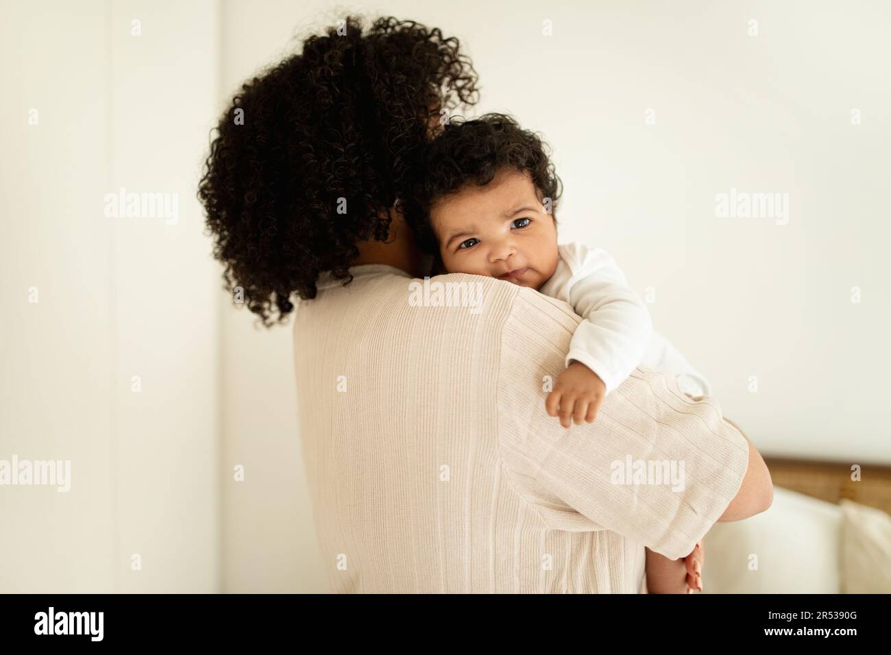 Maman millénaire noire tient le petit bébé mignon dans ses bras, profitez de la maternité dans la chambre légère Banque D'Images