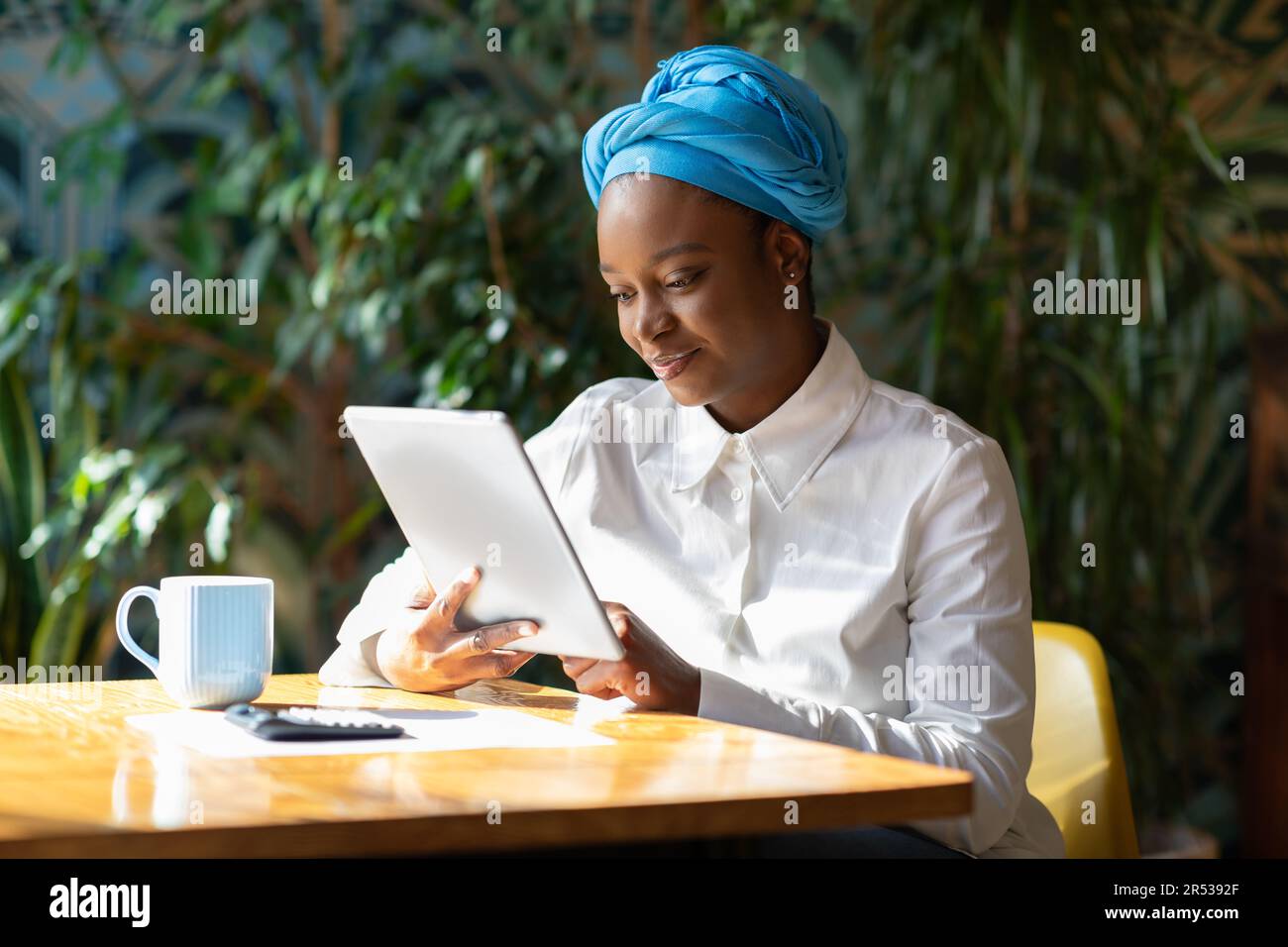 Femme d'affaires réussie utilisant une tablette numérique, calculatrice au café Banque D'Images