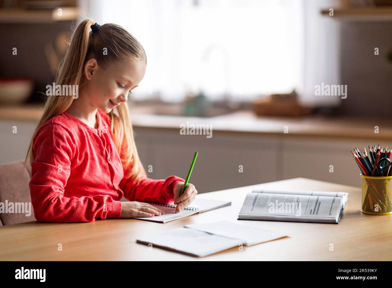 Mignonne petite fille caucasienne faisant des devoirs à l'école, l'écriture et la lecture à la maison Banque D'Images