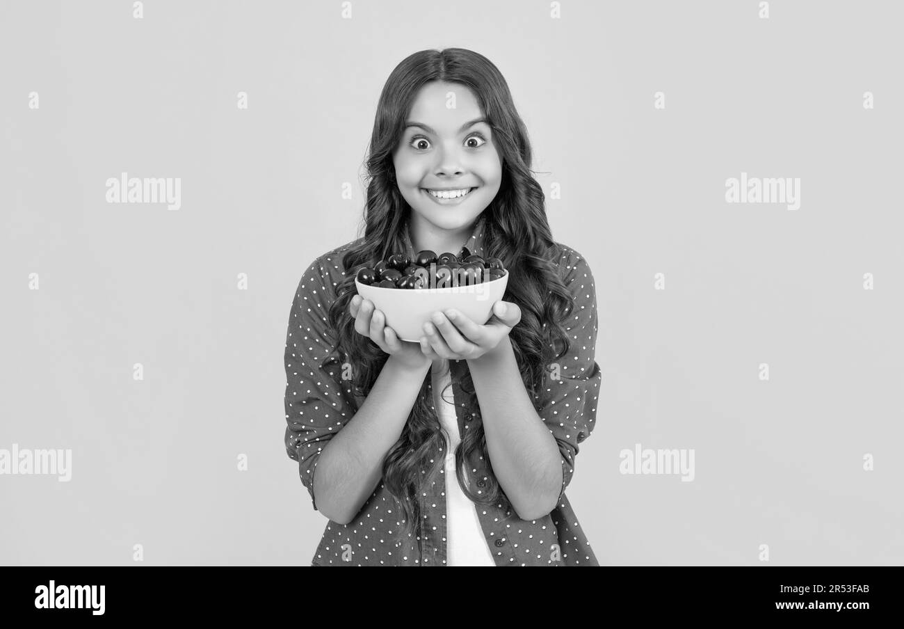 surprise fille de l'adolescence tenir bol de cerise sur fond jaune Banque D'Images