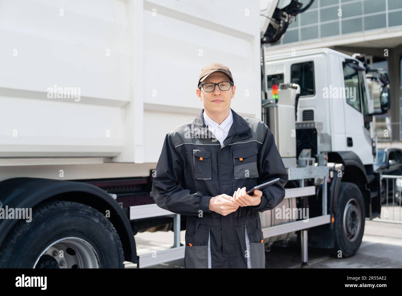 Manager avec une tablette numérique à côté d'un camion à ordures. Photo de haute qualité Banque D'Images