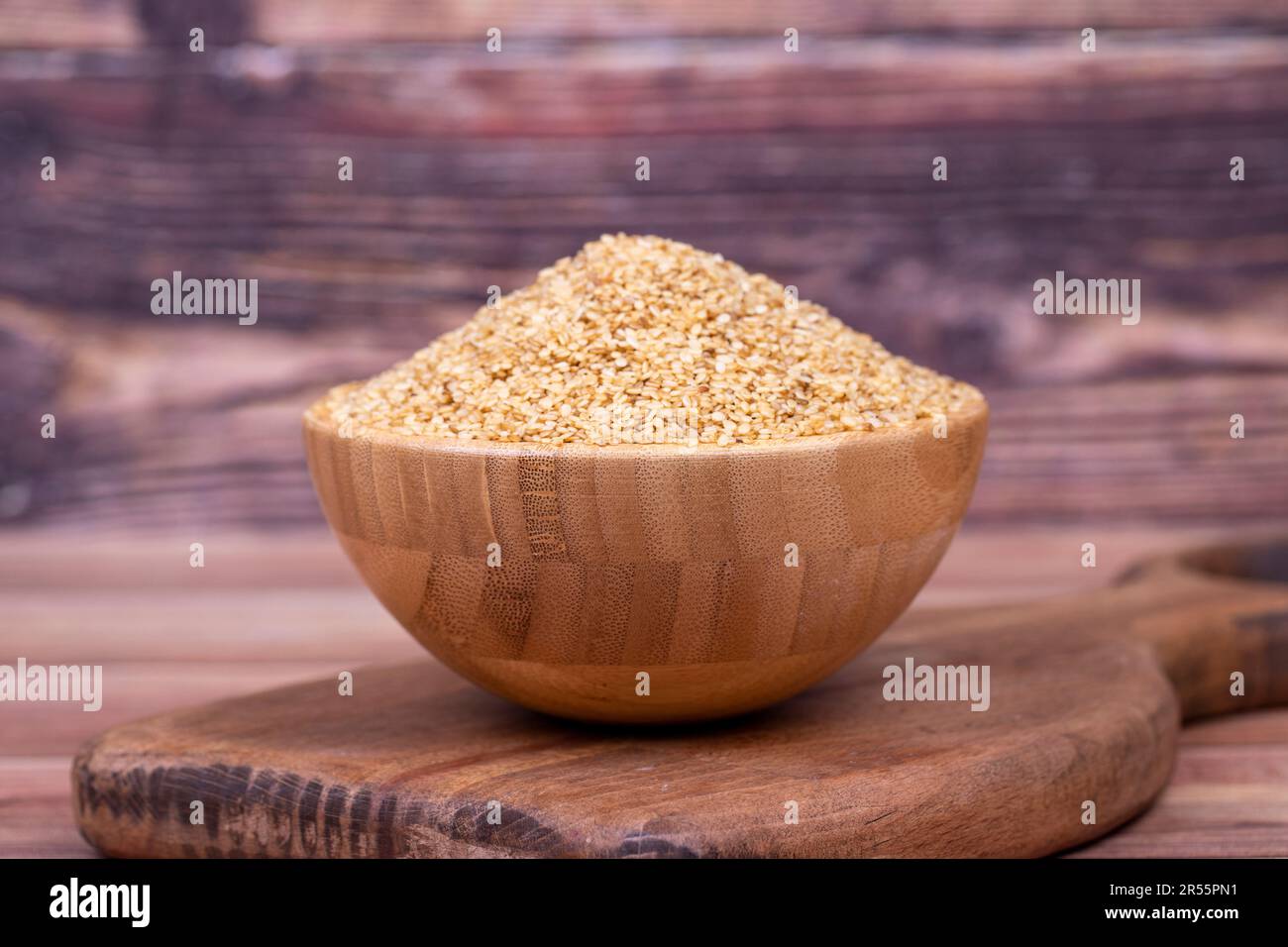 Graines de sésame blanc sur fond de bois. Graines de sésame dans un bol en bois Banque D'Images