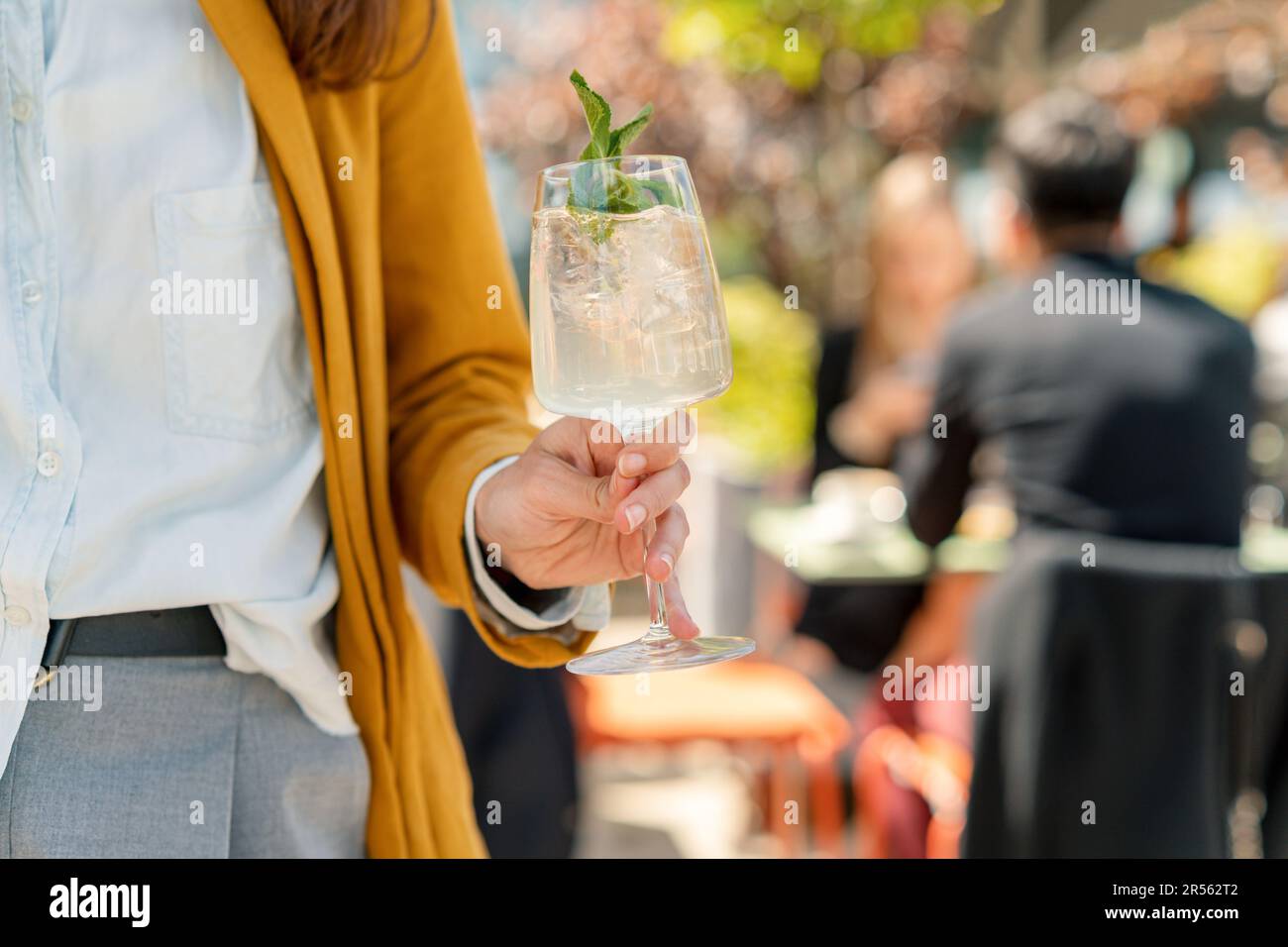 Gros plan d'une femme debout dans un jardin tenant un cocktail hugo Spritz Banque D'Images