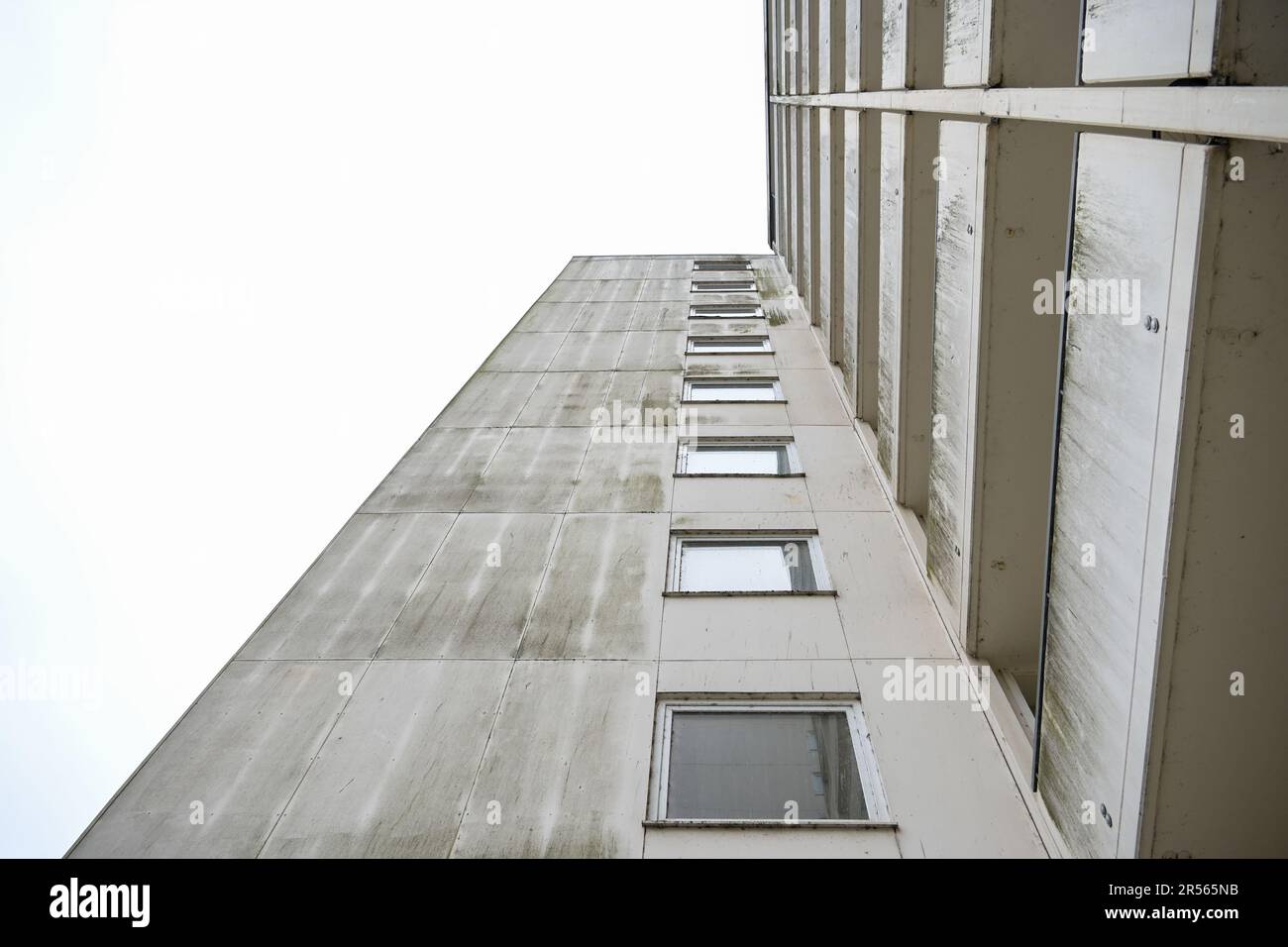 Façade d'un ancien immeuble en hauteur en béton avec balcons et fenêtres, vue d'en dessous, ciel gris, concept immobilier et immobilier, co Banque D'Images