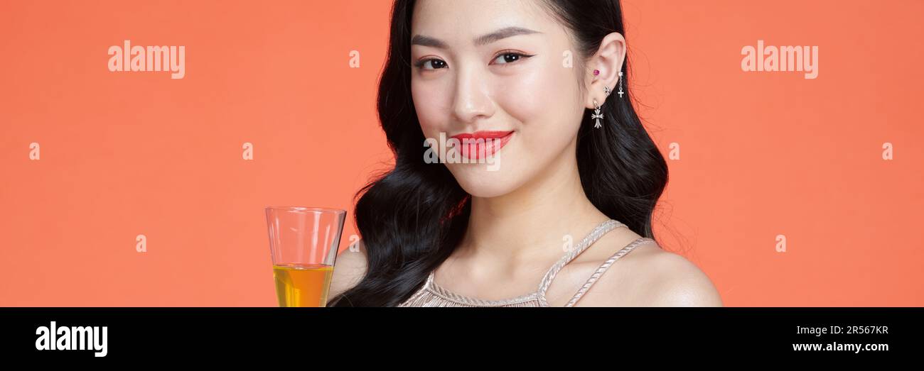 Belle fille asiatique en soirée robe souriante, tenant un verre de champagne Banque D'Images