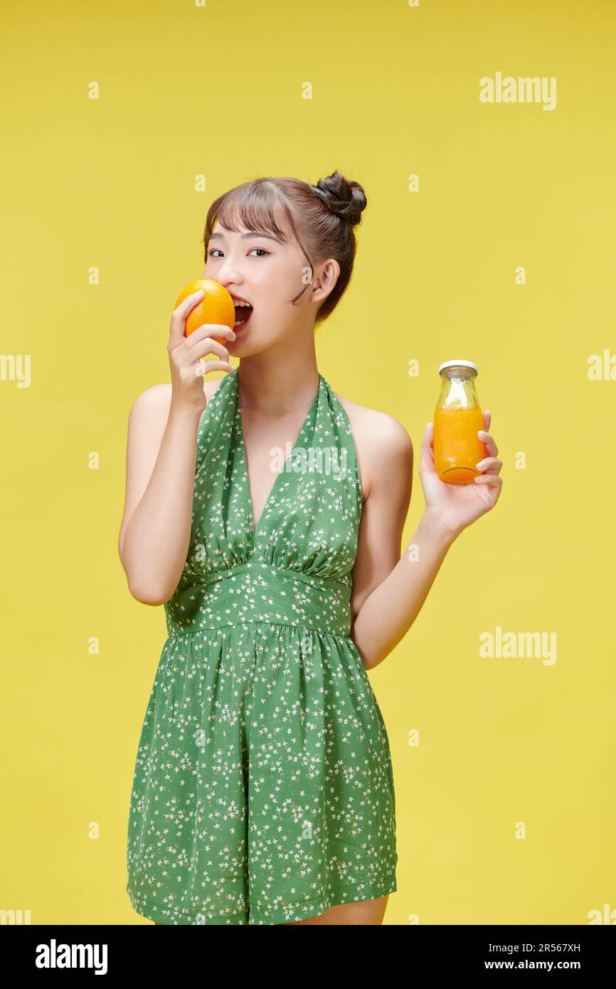 Portrait d'une jeune femme tenant une orange et un verre de jus d'orange frais Banque D'Images