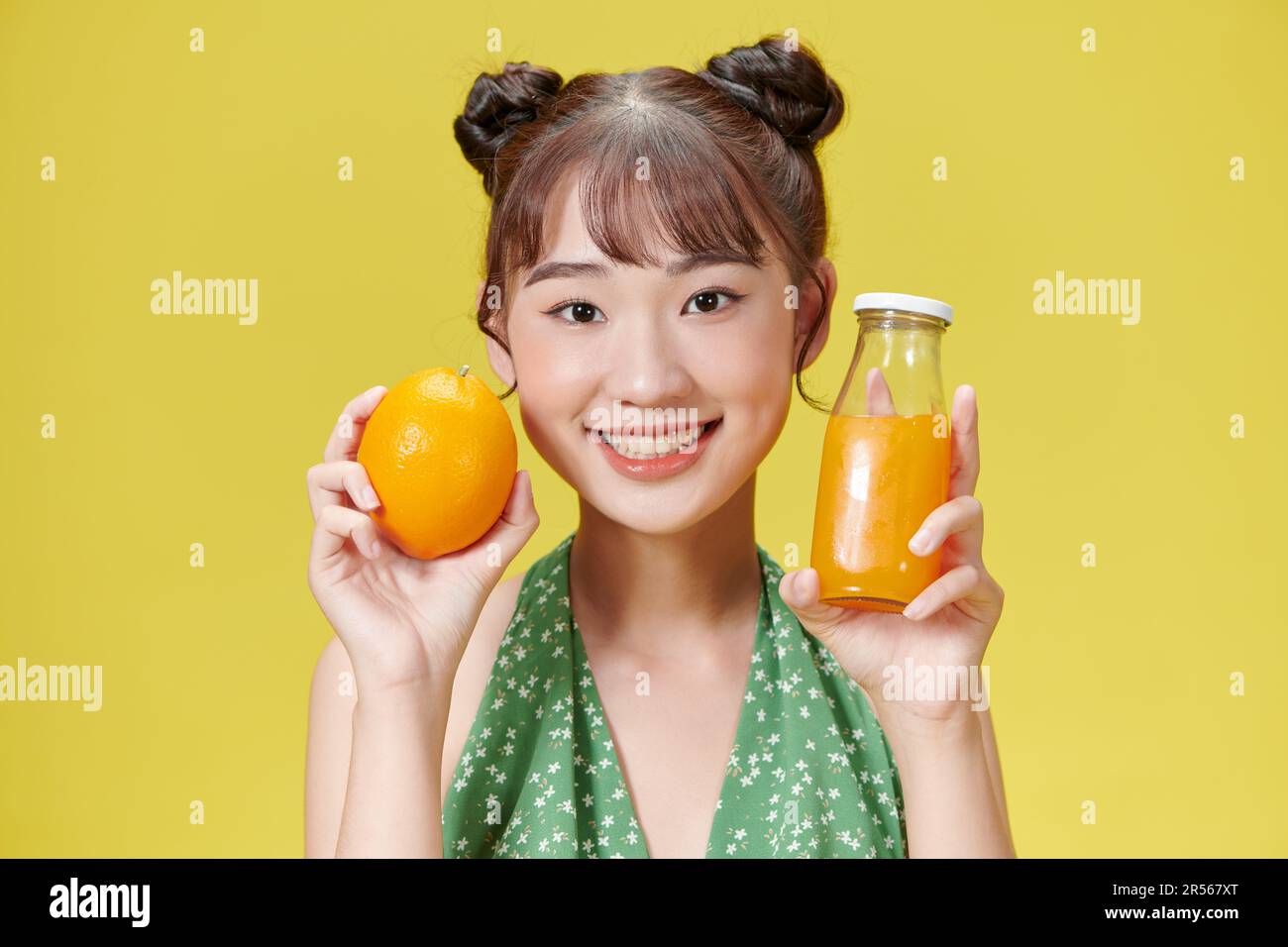 une belle jeune femme avec un verre de jus et d'orange, sur fond jaune. Banque D'Images