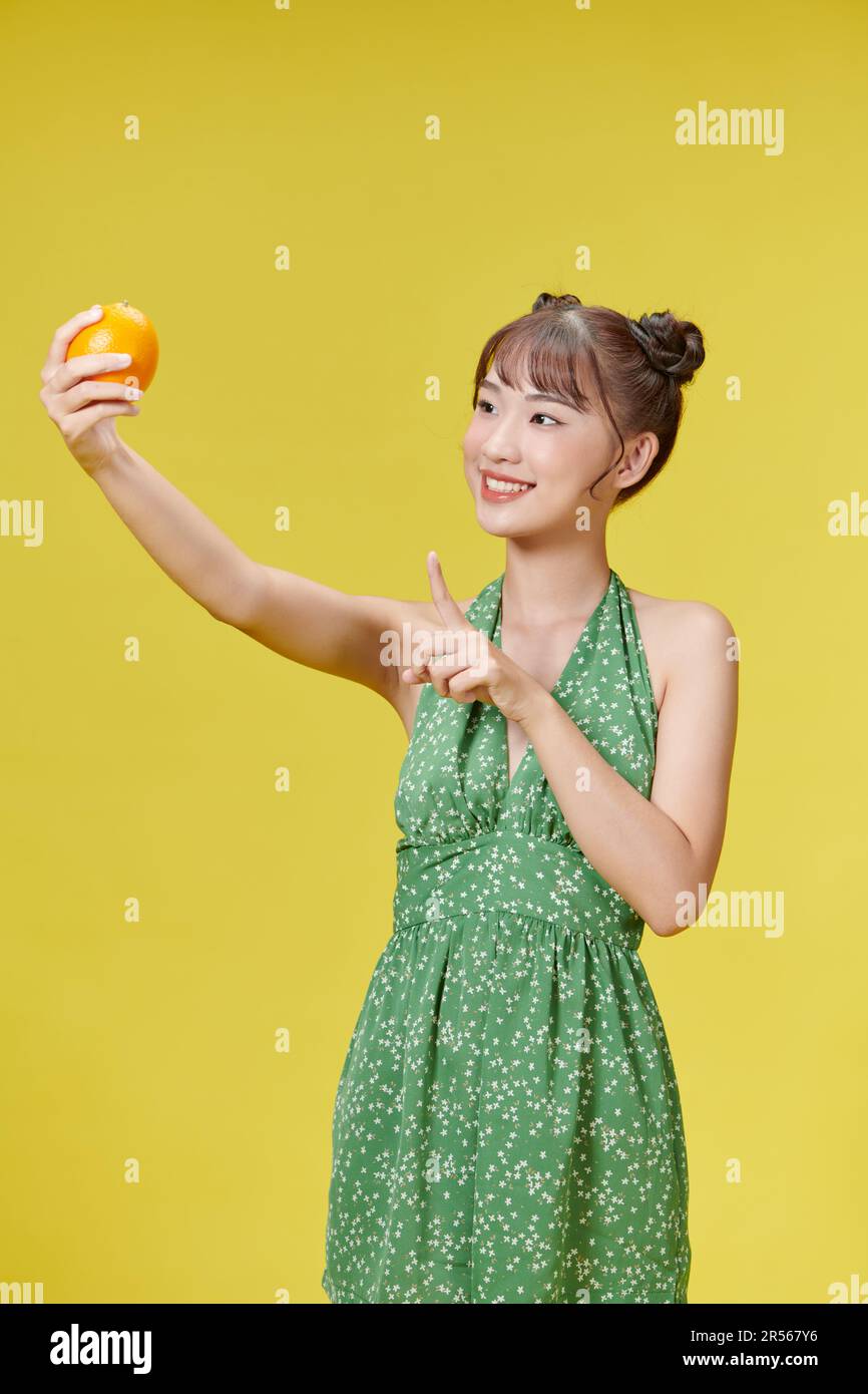 Jeune femme asiatique tenant l'orange frais souriant heureux pointant avec la main et le doigt Banque D'Images