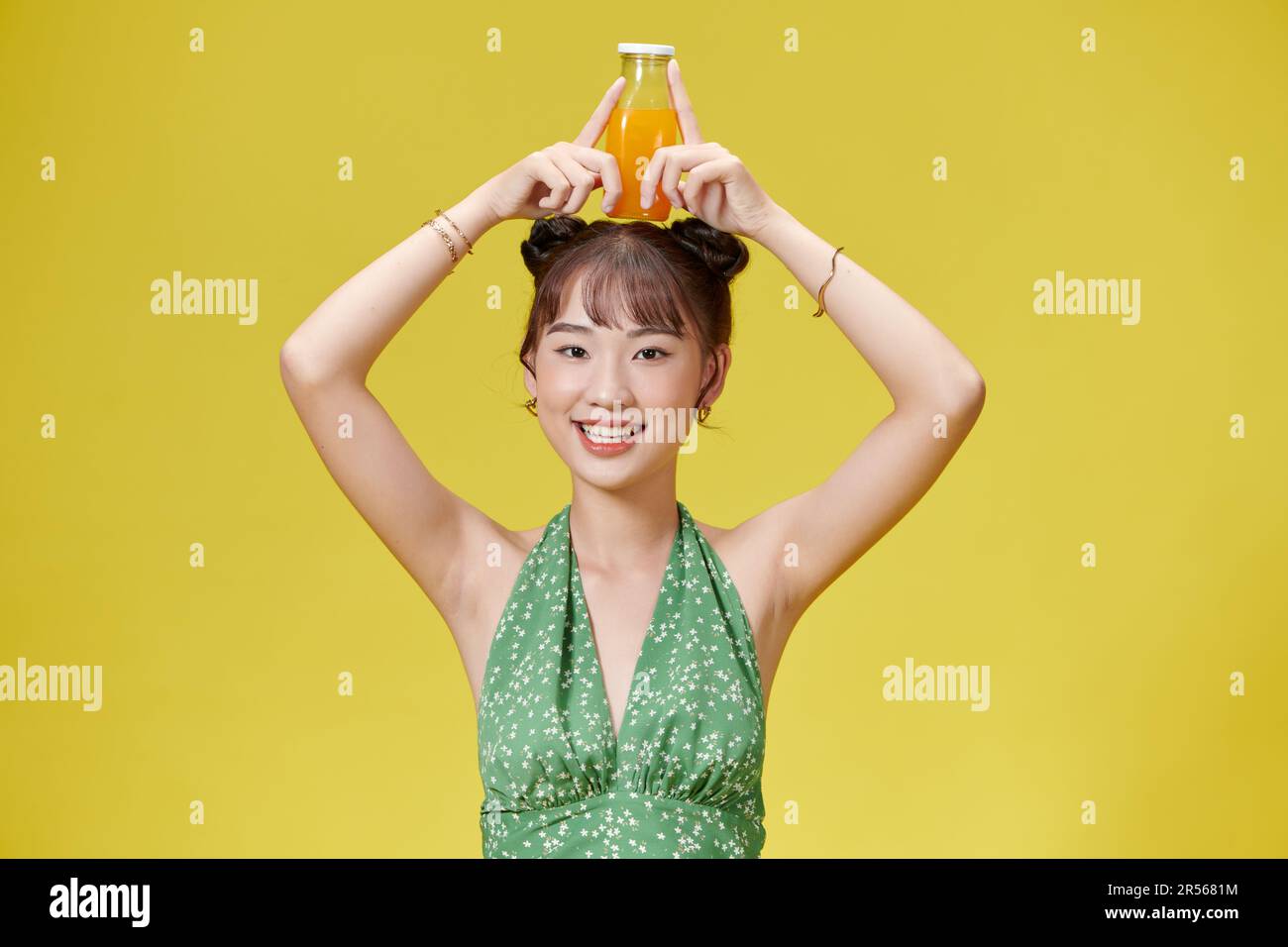 Sourire heureux asiatique jeune femme boire du jus d'orange frais dans une bouteille de verre Banque D'Images