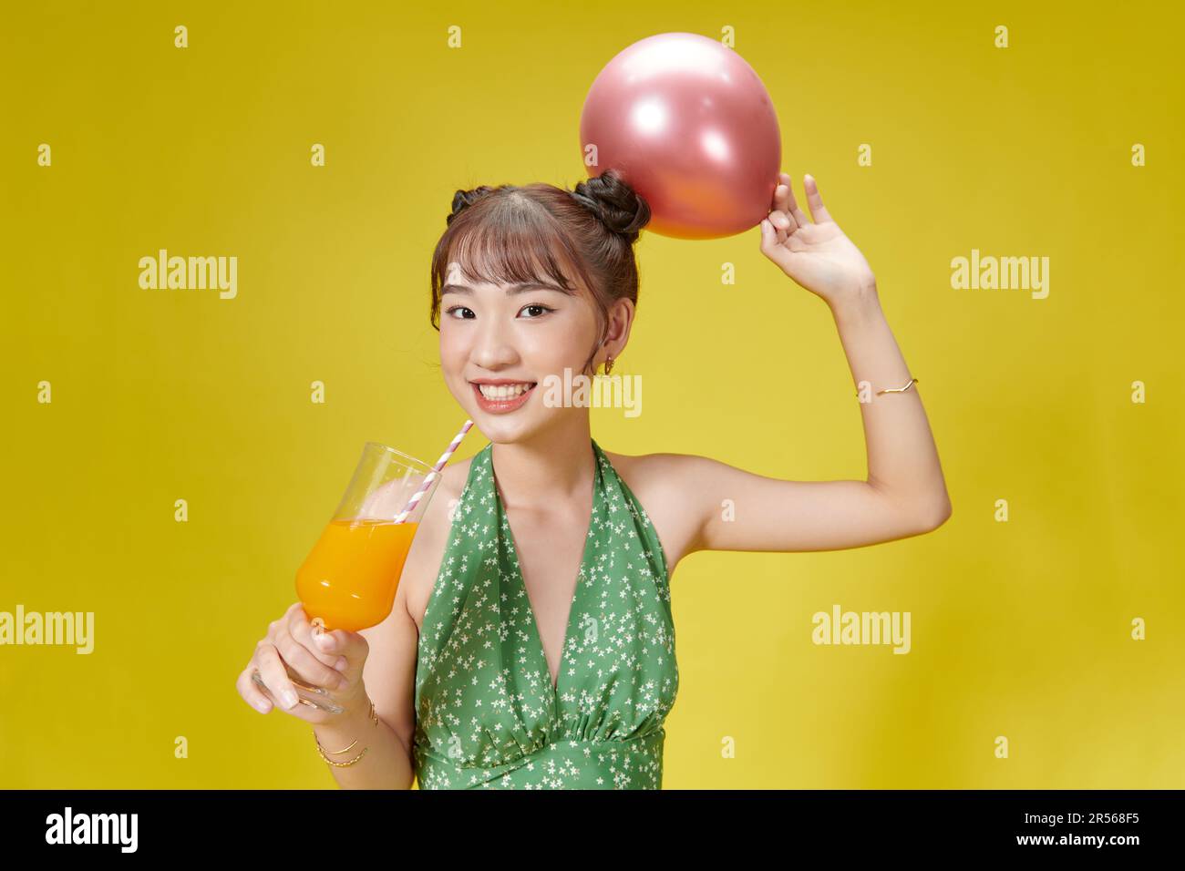 Adorable femme tenant un verre avec une boisson tropicale à la main isolée sur fond vif Banque D'Images