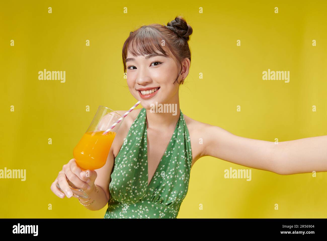 Portrait d'été de la belle femme asiatique tenant une boisson de jus de fruit sur fond jaune Banque D'Images