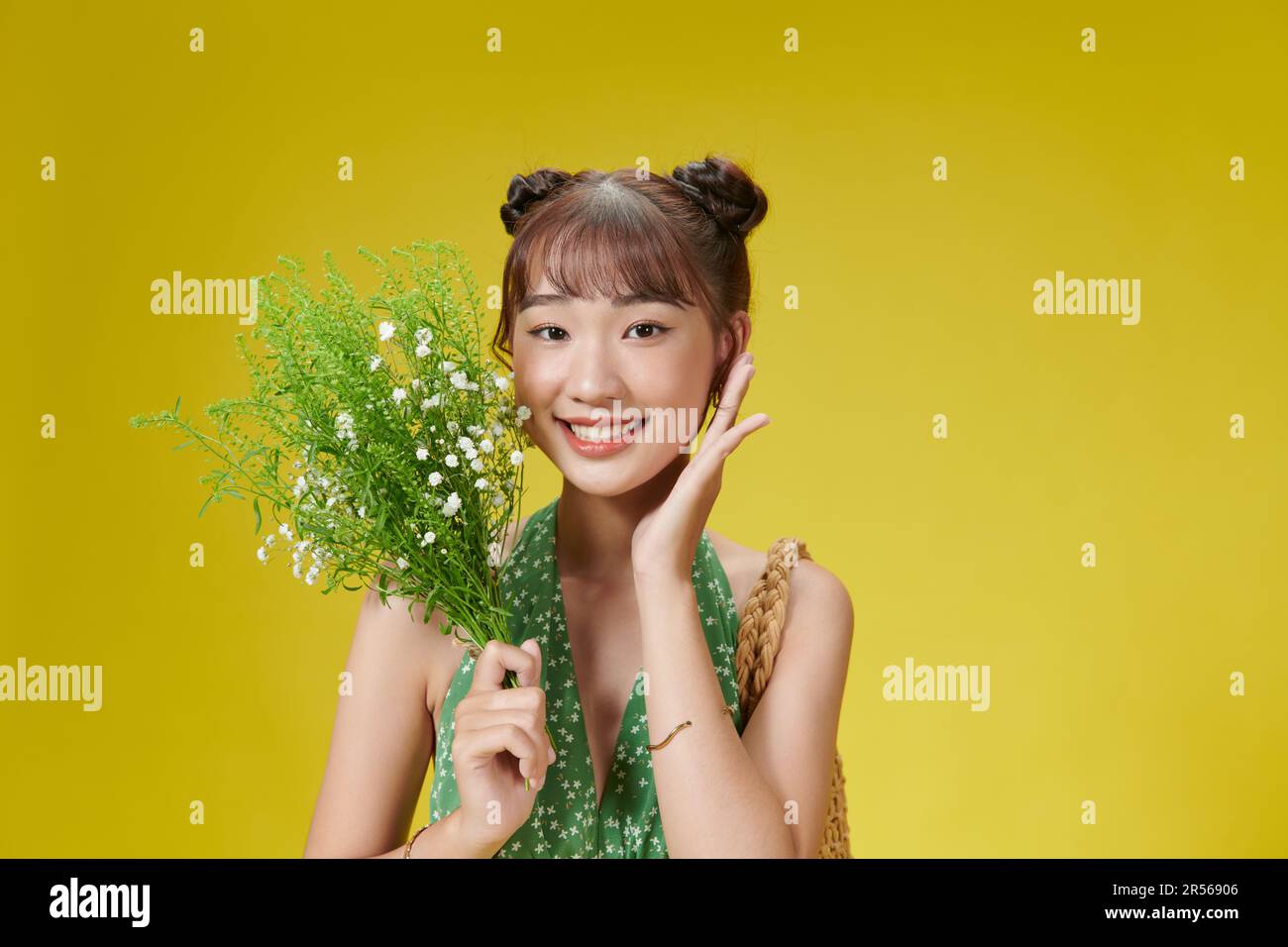 Portrait d'une femme asiatique attrayante avec bouquet de fleurs en chambre jaune Banque D'Images