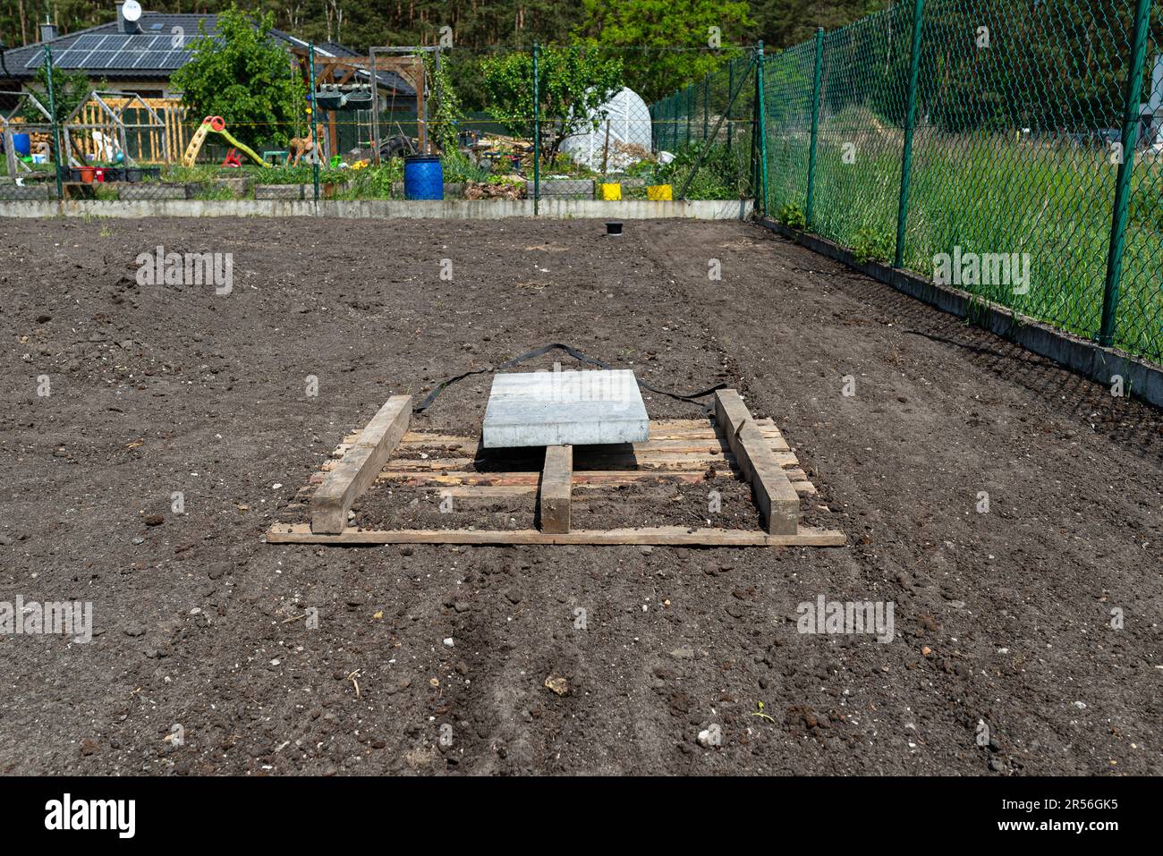 Nivellement du chernozem dans la cour avec une palette pondérée avec un cube en béton, en préparation pour semer la pelouse. Banque D'Images