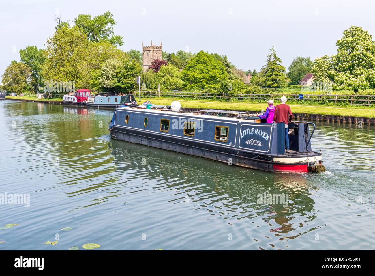 Un long bateau sur le canal Gloucester et Sharpness passant par l'église St Marys au pont Splatt dans le village Severnside de Frampton sur Severn, Gloucester Banque D'Images