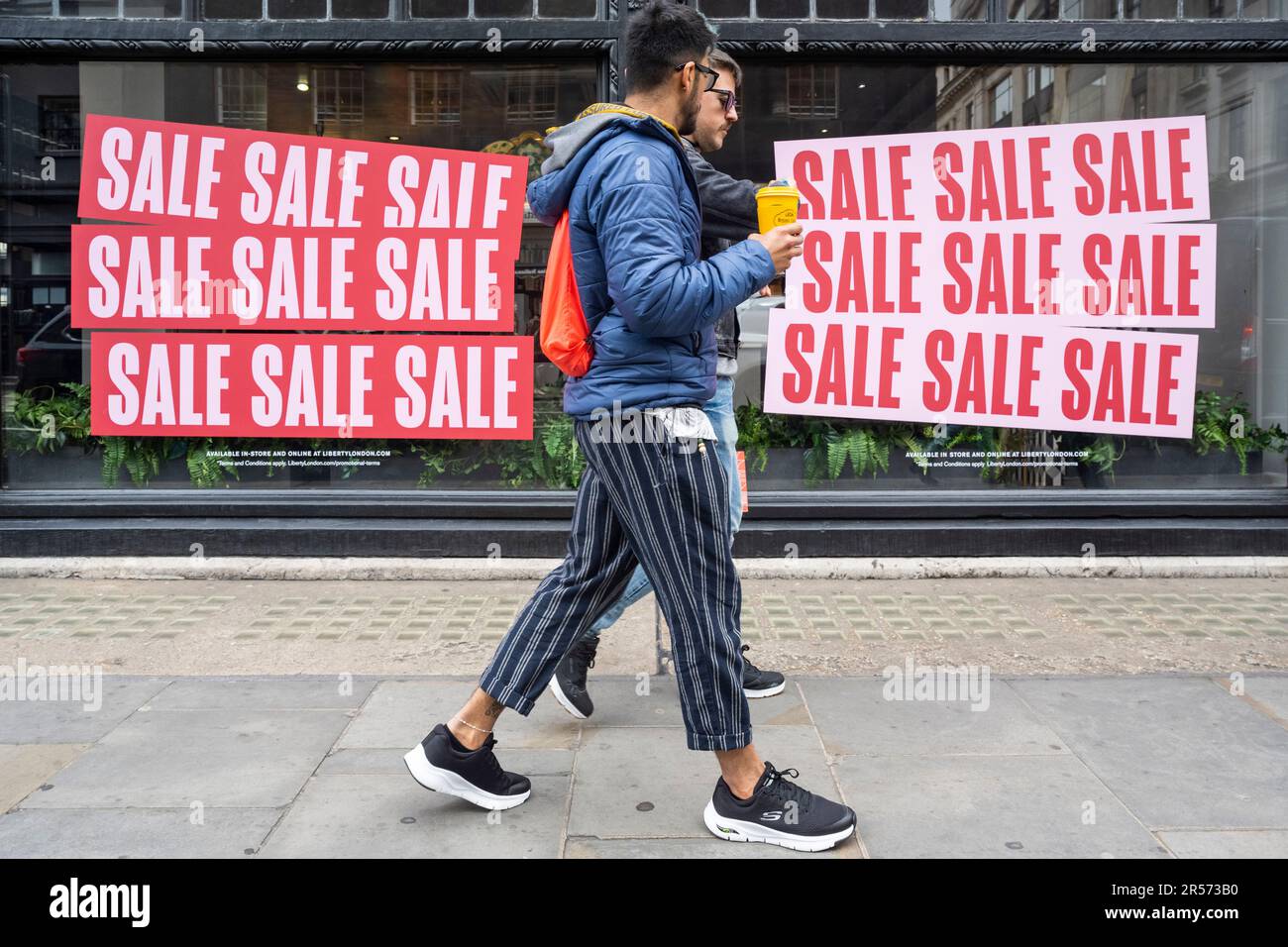 Londres, Royaume-Uni. 1 juin 2023. Les hommes passent les fenêtres du grand magasin Liberty sur Regent Street qui ont été décorés avec des affiches de vente d'été. Des représentants des secteurs de l’accueil, de la vente au détail et du tourisme demandent que la décision du Trésor d’annuler l’exemption de TVA pour les touristes étrangers soit annulée. L'Association of International Retail a signalé que, bien que les dépenses touristiques britanniques soient de retour aux niveaux d'avant la pandémie de 2019, ces dépenses en France, en Allemagne, en Espagne et en Italie sont deux ou trois fois plus élevées que celles d'avant Covid et la différence est expliquée au Royaume-Uni par ce que l'on appelle la «ta touristique» Banque D'Images