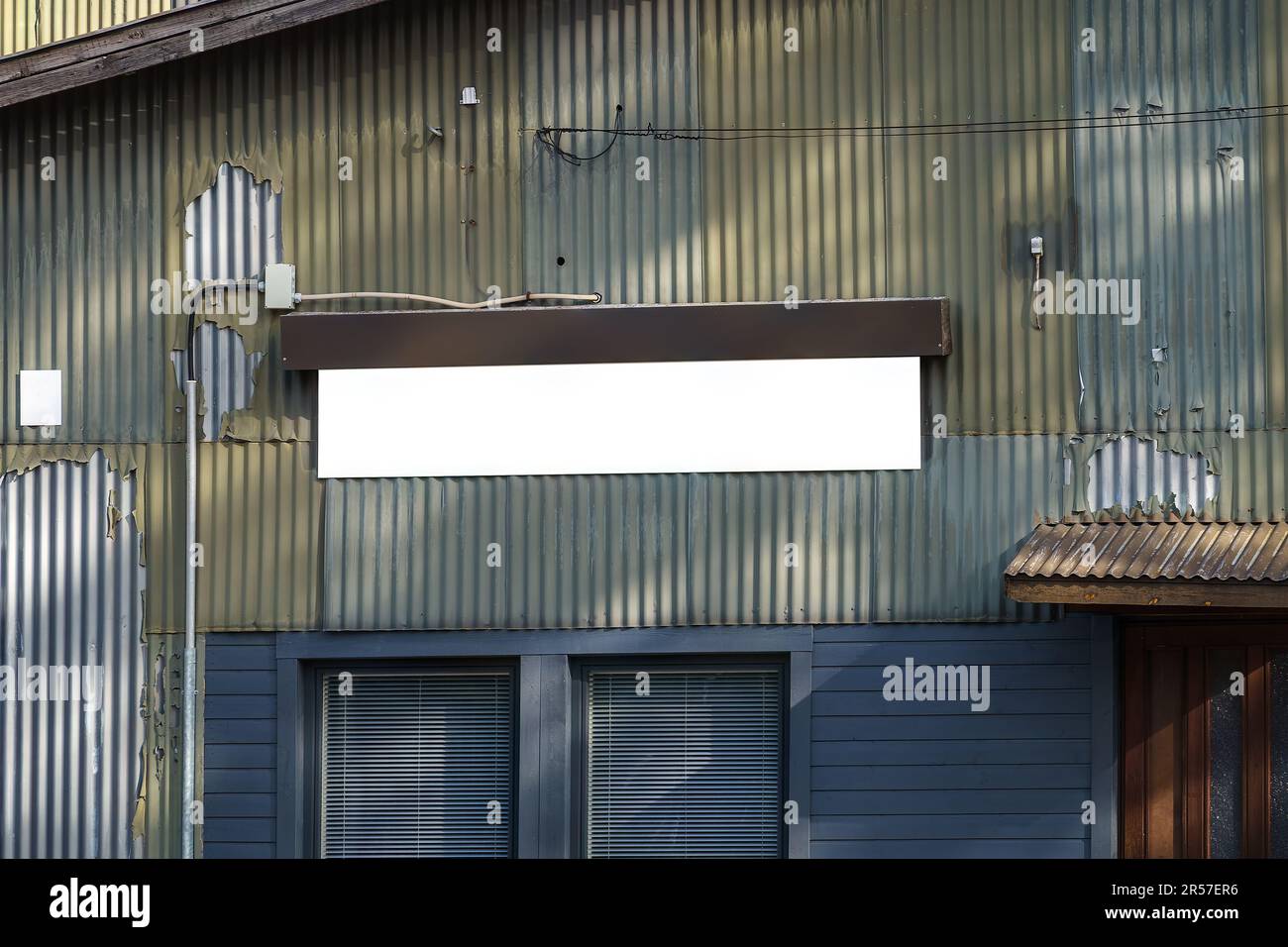 Affiche blanche vide sur un mur métallique d'un ancien bâtiment industriel. Banque D'Images