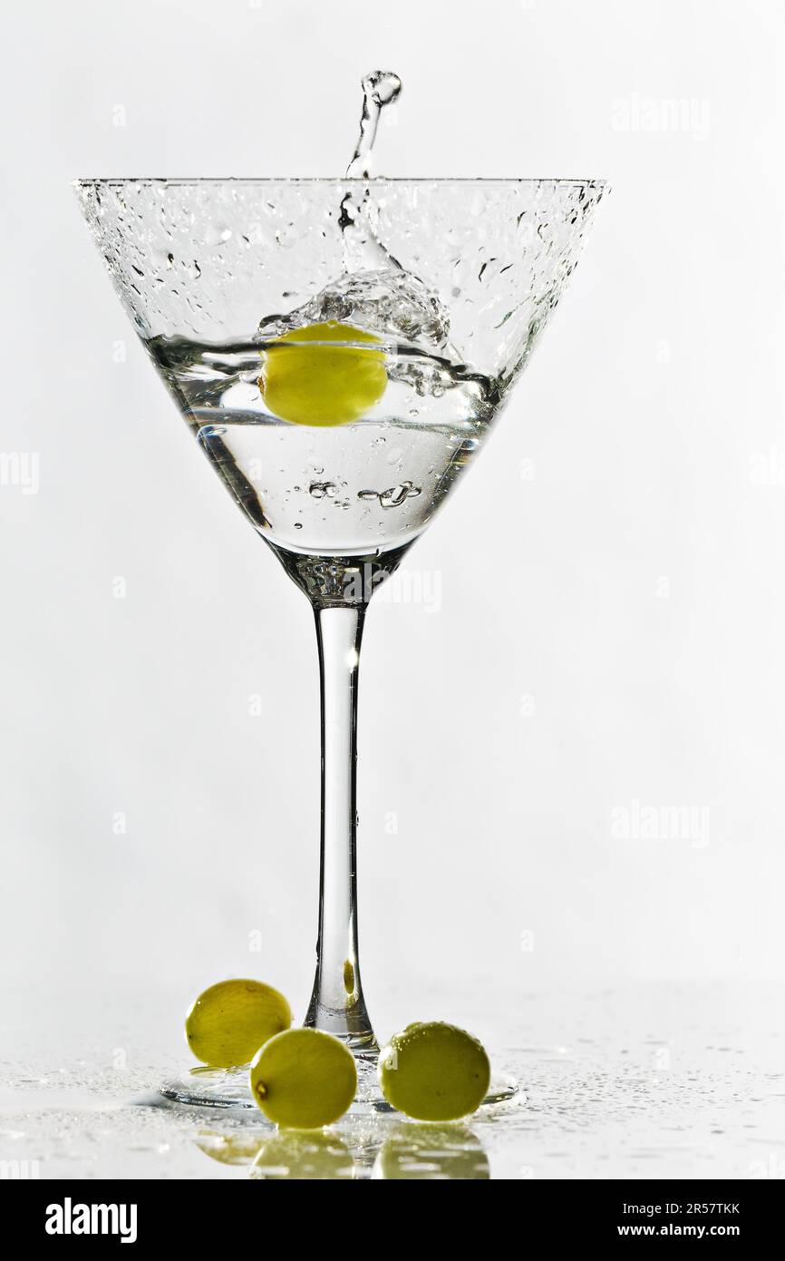 Verre à cocktail isolé sur fond blanc avec des raisins verts Banque D'Images
