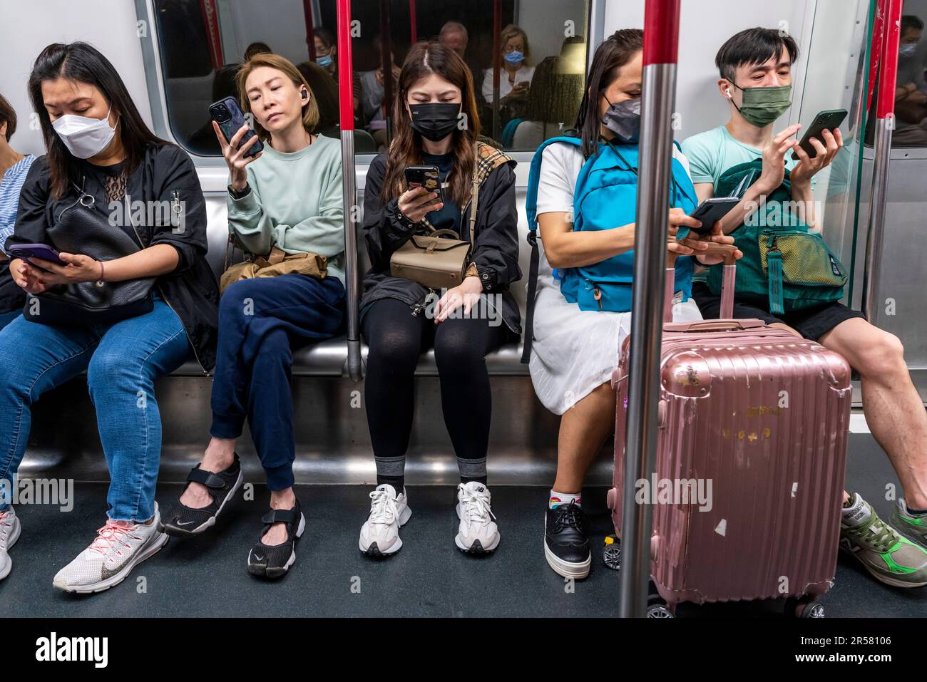 Personnes utilisant leur smartphone sur Un train MTR, Hong Kong, Chine. Banque D'Images