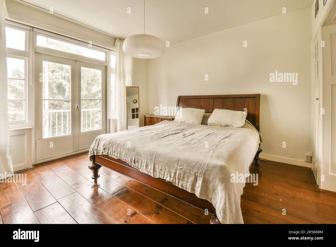 une chambre avec parquet et murs blancs, dont un grand lit au centre de la  chambre est une tête de lit en bois Photo Stock - Alamy