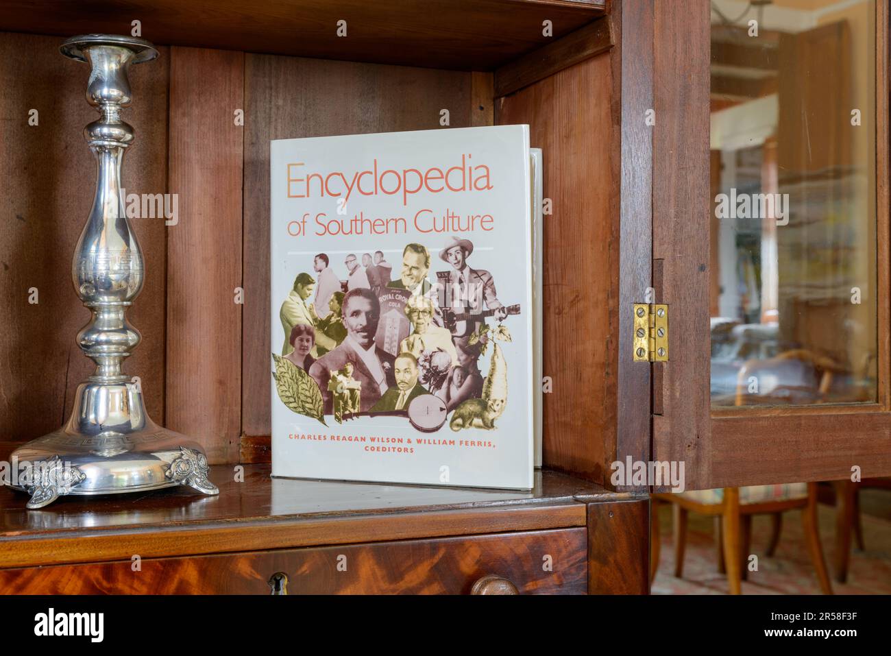 NEW ORLEANS, LA, USA - 24 MAI 2023 : l'Encyclopédie de la culture du Sud est présentée à côté d'un porte-bougie argenté dans un cabinet de chine ouvert Banque D'Images