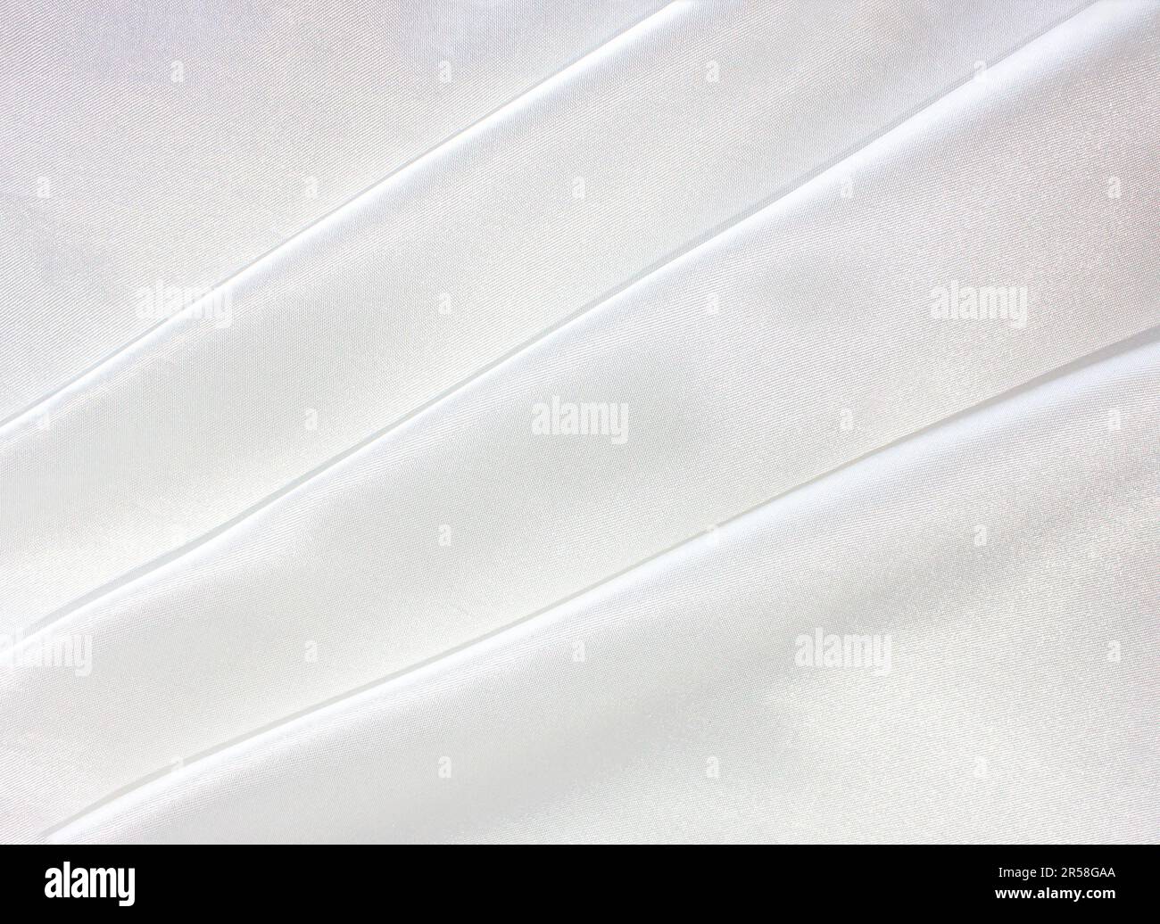 Gros plan sur un tissu en soie blanc ondulé. Satin blanc. Courbes droites et élégantes en soie brillante de luxe, tissu satiné. Banque D'Images
