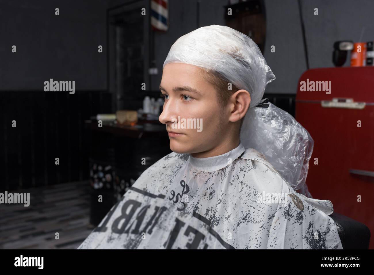 Jeune gars beau client barbershop portrait processus de teinture professionnelle de cheveux dans le coiffeur. Banque D'Images