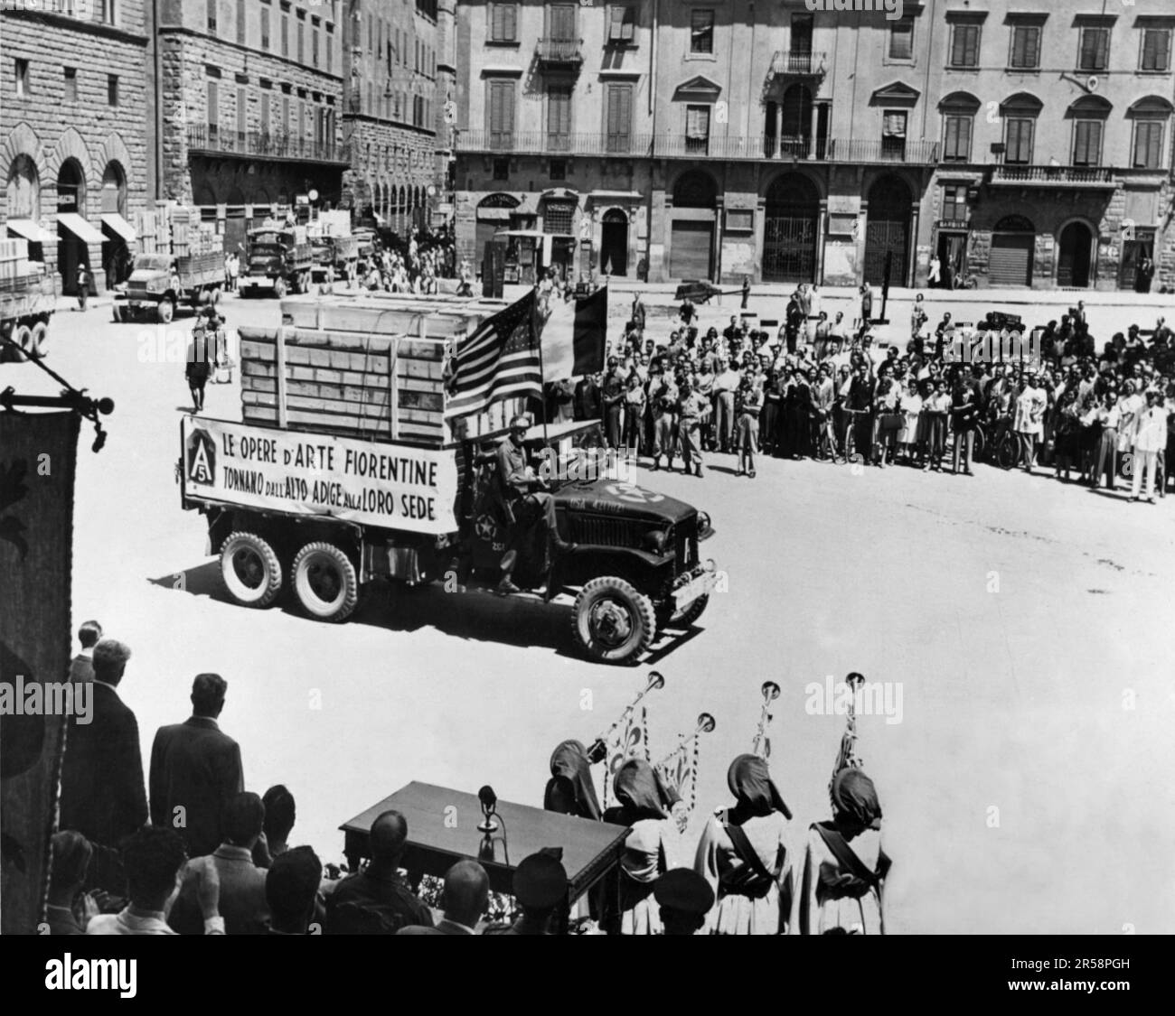 1945 , 25 juillet , Florence , ITALIE : les italiens accueillent les trésors d'art de la maison volés par les Allemands et retournés par les Américains. L'art florentin est retourné. ÉTATS-UNIS Les camions de la cinquième armée avec une partie du milliard de dollars de trésors d'art volés par les Allemands arrivent à la Plaza Signoria, Florence . Les trompettistes gardés en costume médiéval ( les quelques survivants de la guerre ) se tiennent devant le stand de revue pour accueillir le retour des peintures inestimables qui avaient été cachées par les Allemands sur la haute rivière Adige près de Bolzano ( Trentin-Haut-Adige ), en Italie du Nord . Les peintures ont été présentées au maire de Banque D'Images