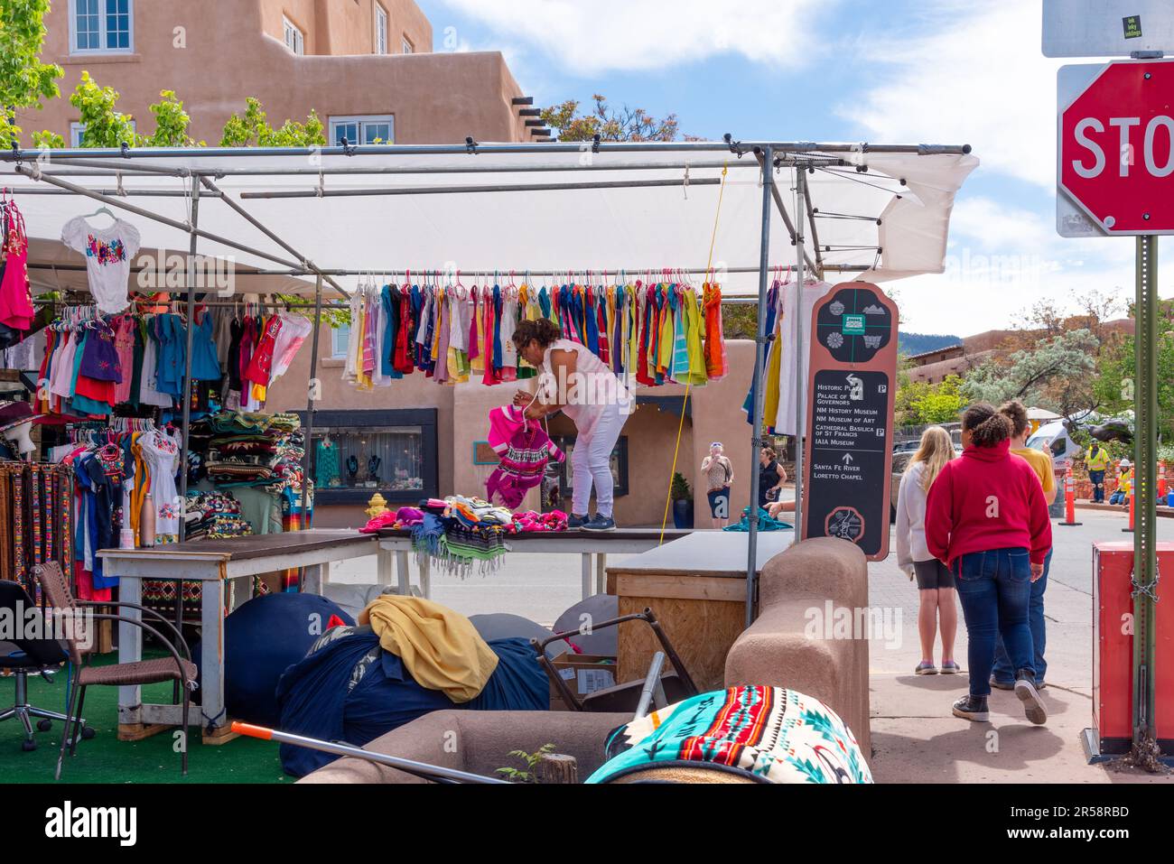 Une femme vendeur se lache de mettre son stand en place pour la journée à accrocher des vêtements importés probablement du Mexique ou d'Amérique centrale -- Santa Fe, Nouveau-Mexique, États-Unis Banque D'Images