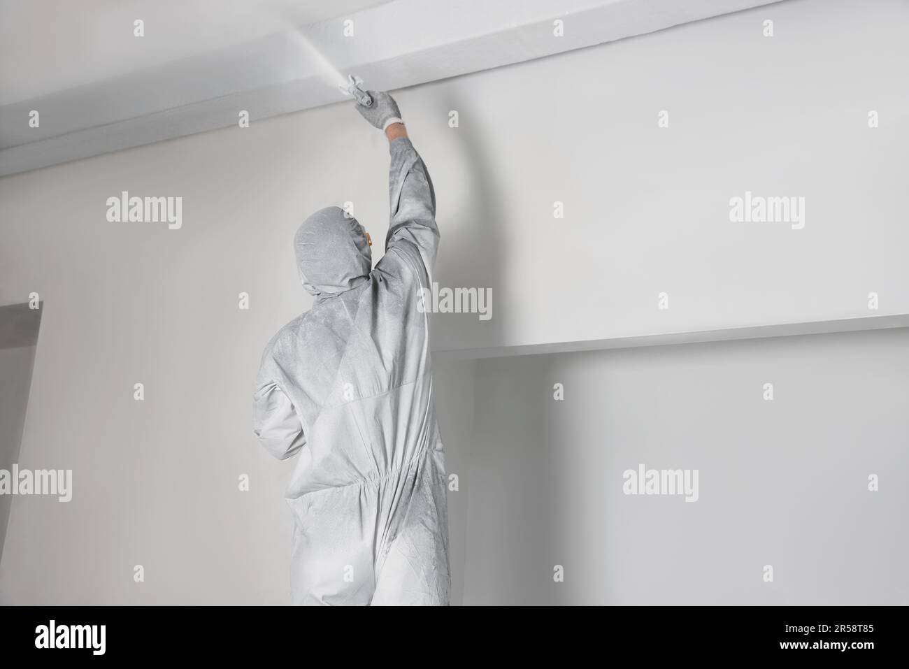 Décoration dans des combinaisons de protection pour peindre le plafond avec  pistolet à pulvériser à l'intérieur Photo Stock - Alamy