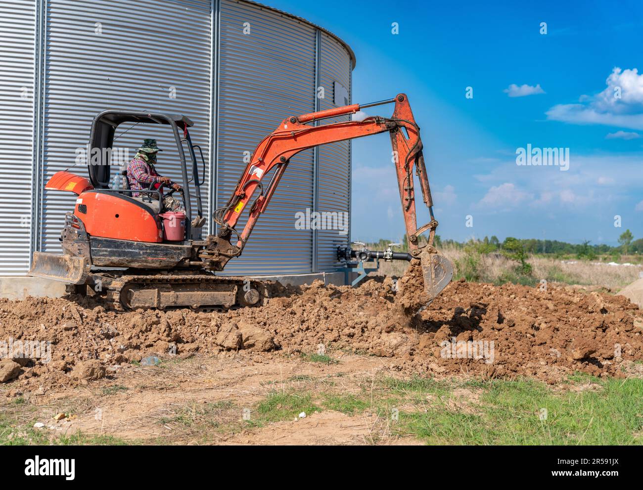 Une minipelle creuse une tranchée sur un chantier de construction. Pose de sous-sol autour des fondations. Banque D'Images