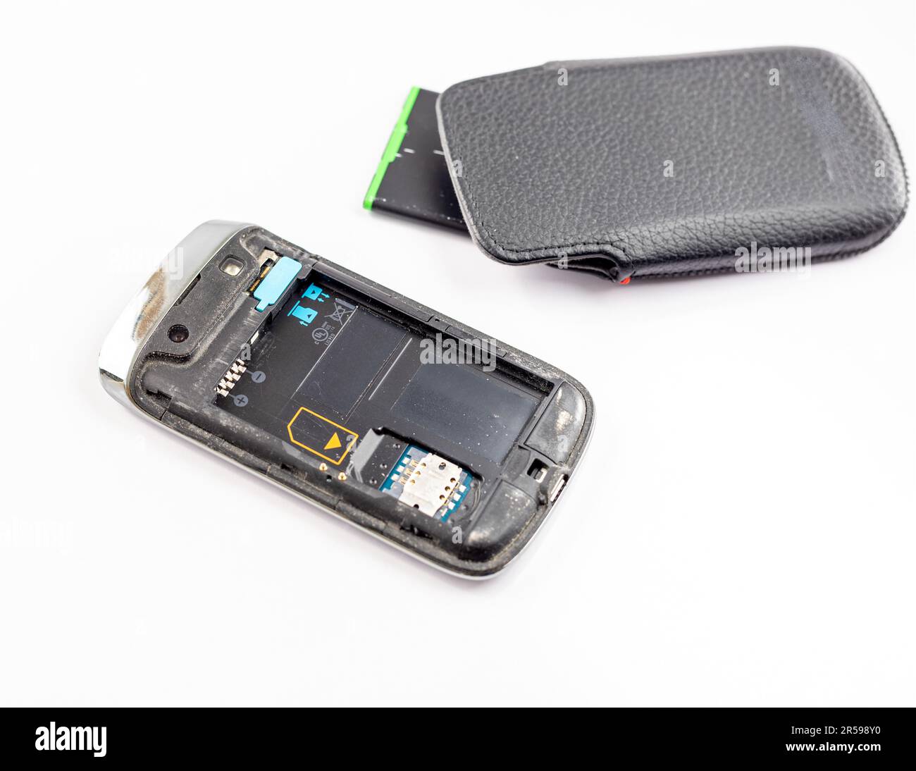 Couvercle arrière du téléphone portable et batterie retirés avec un étui en cuir noir sur fond blanc isolé Banque D'Images