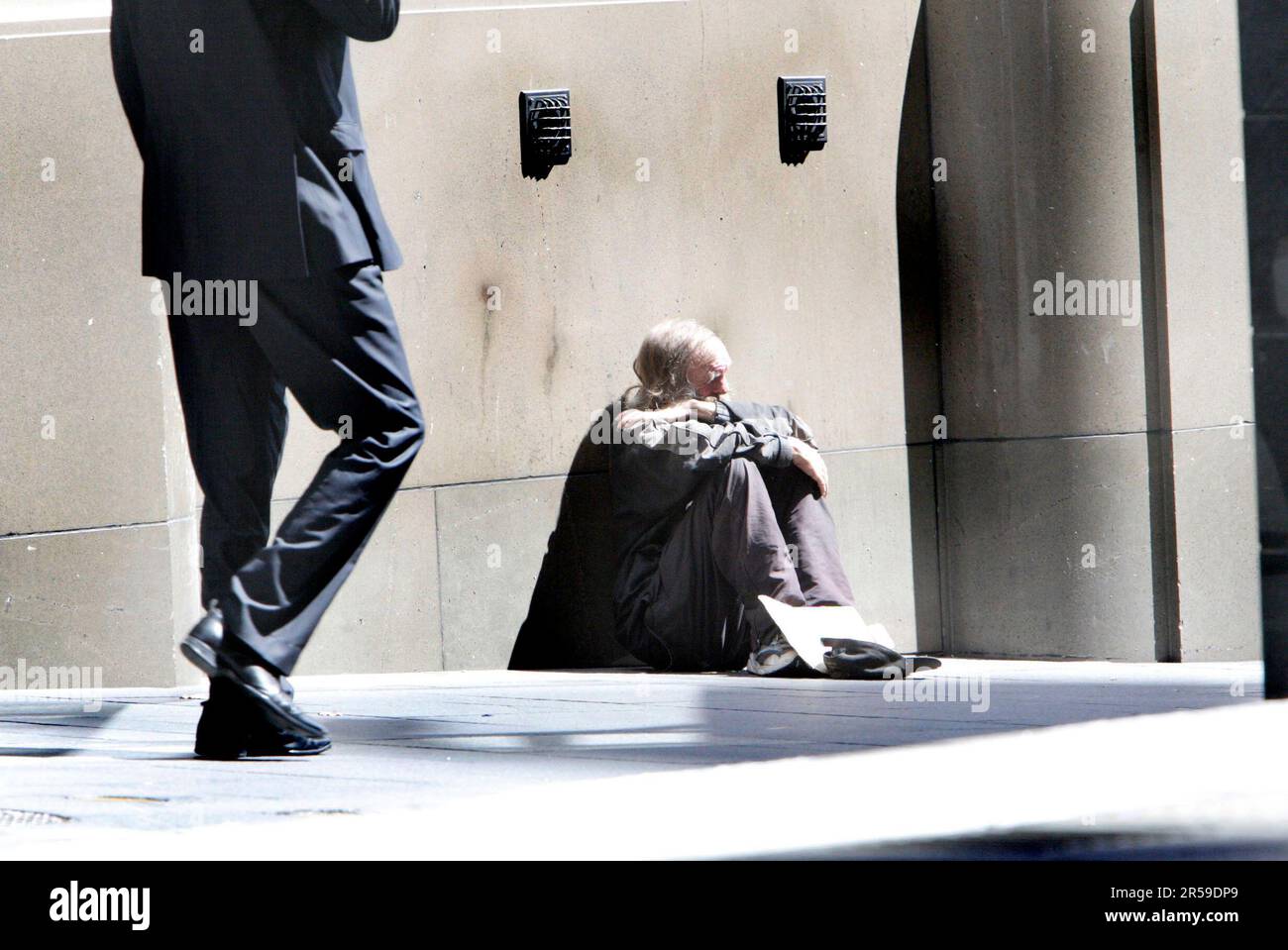 Un homme sans abri supplie avec l'aide d'un écriteau à Martin place à Sydney. Banque D'Images