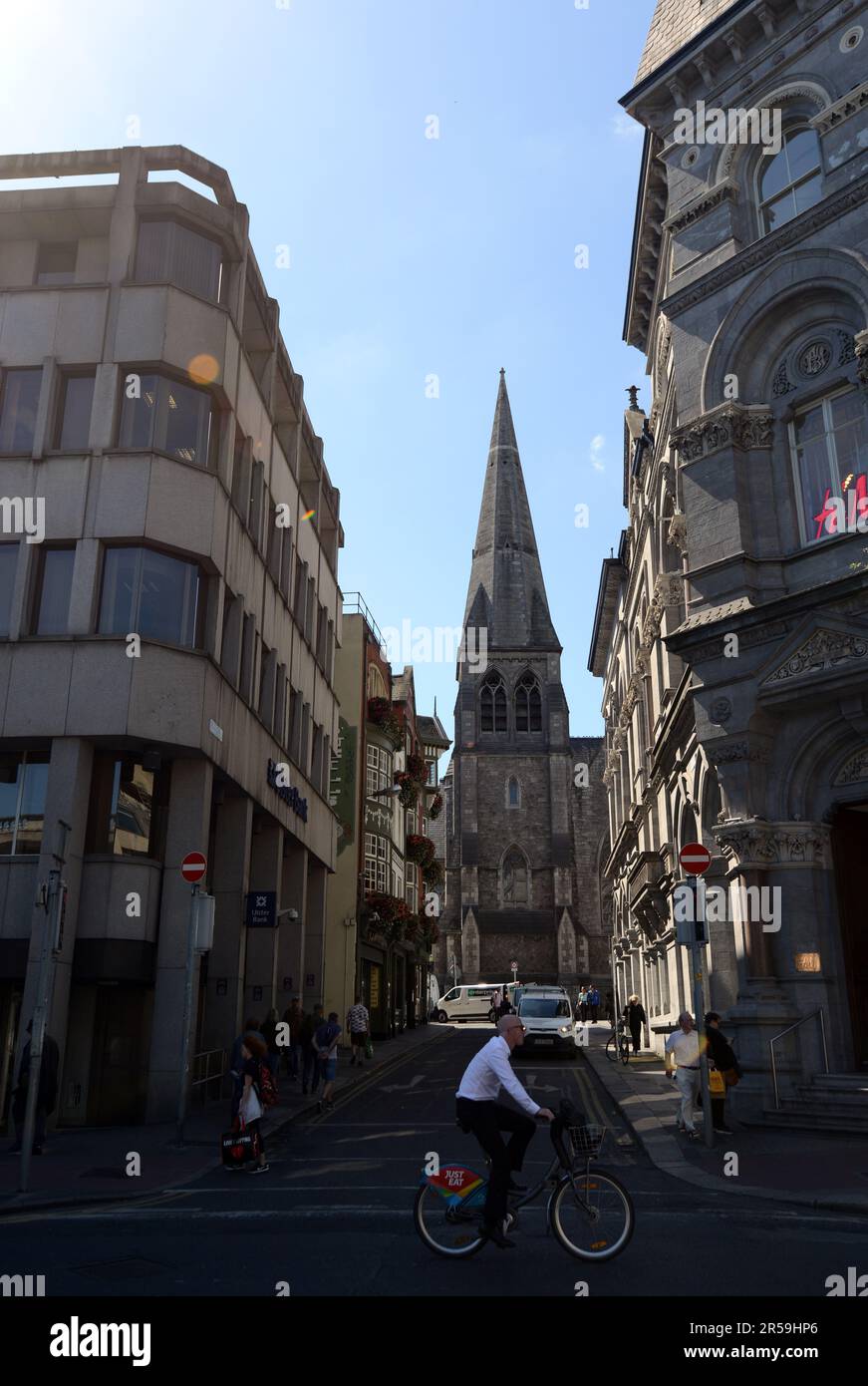 Un irlandais qui monte à vélo sur la rue Dame avec la rue St. L'église d'Andrew en arrière-plan. Dublin, Irlande. Banque D'Images