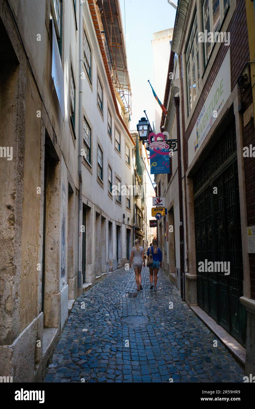 Deux jeunes femmes touristes marchant le long de l'une des rues étroites du quartier d'Alfama à Lisbonne Banque D'Images
