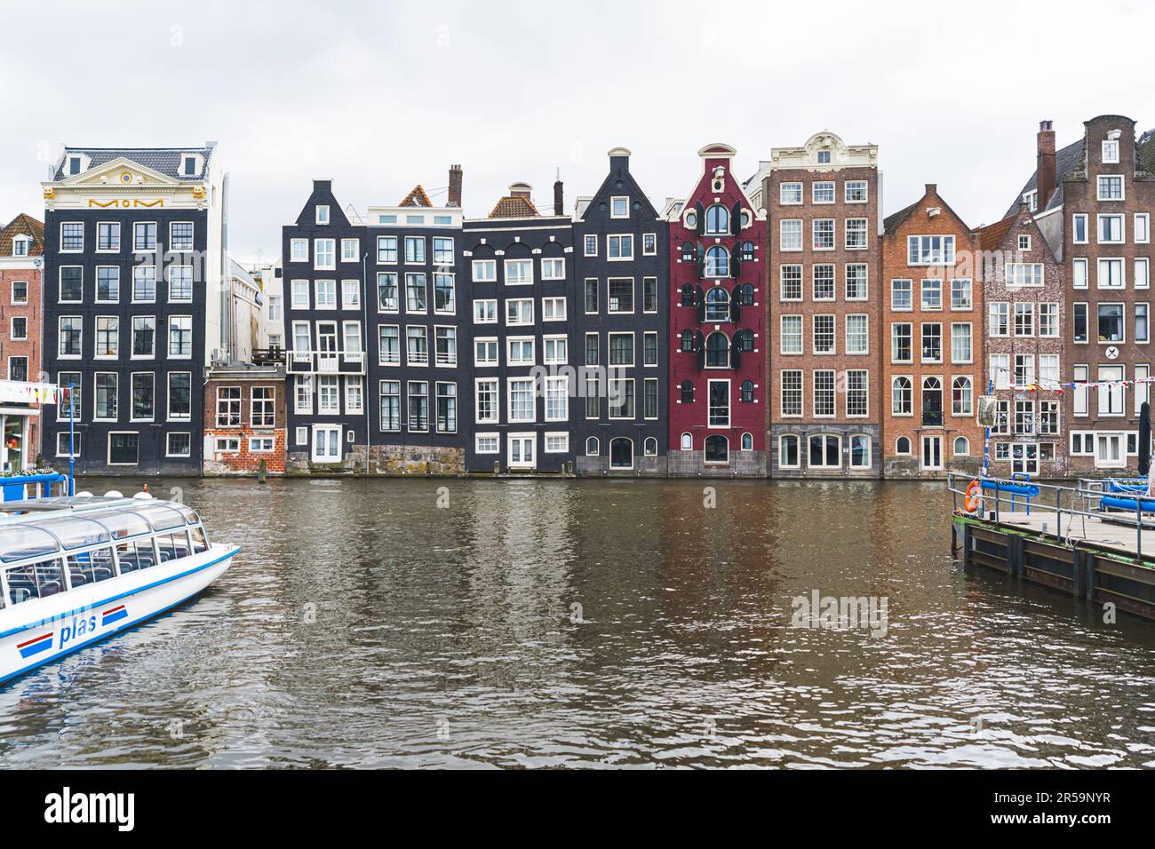Les maisons dansant d'Amsterdam. Hauts bâtiments colorés construits le long du canal. Maisons dansantes sur le canal de Damrak. Temps nuageux. Photo de haute qualité Banque D'Images