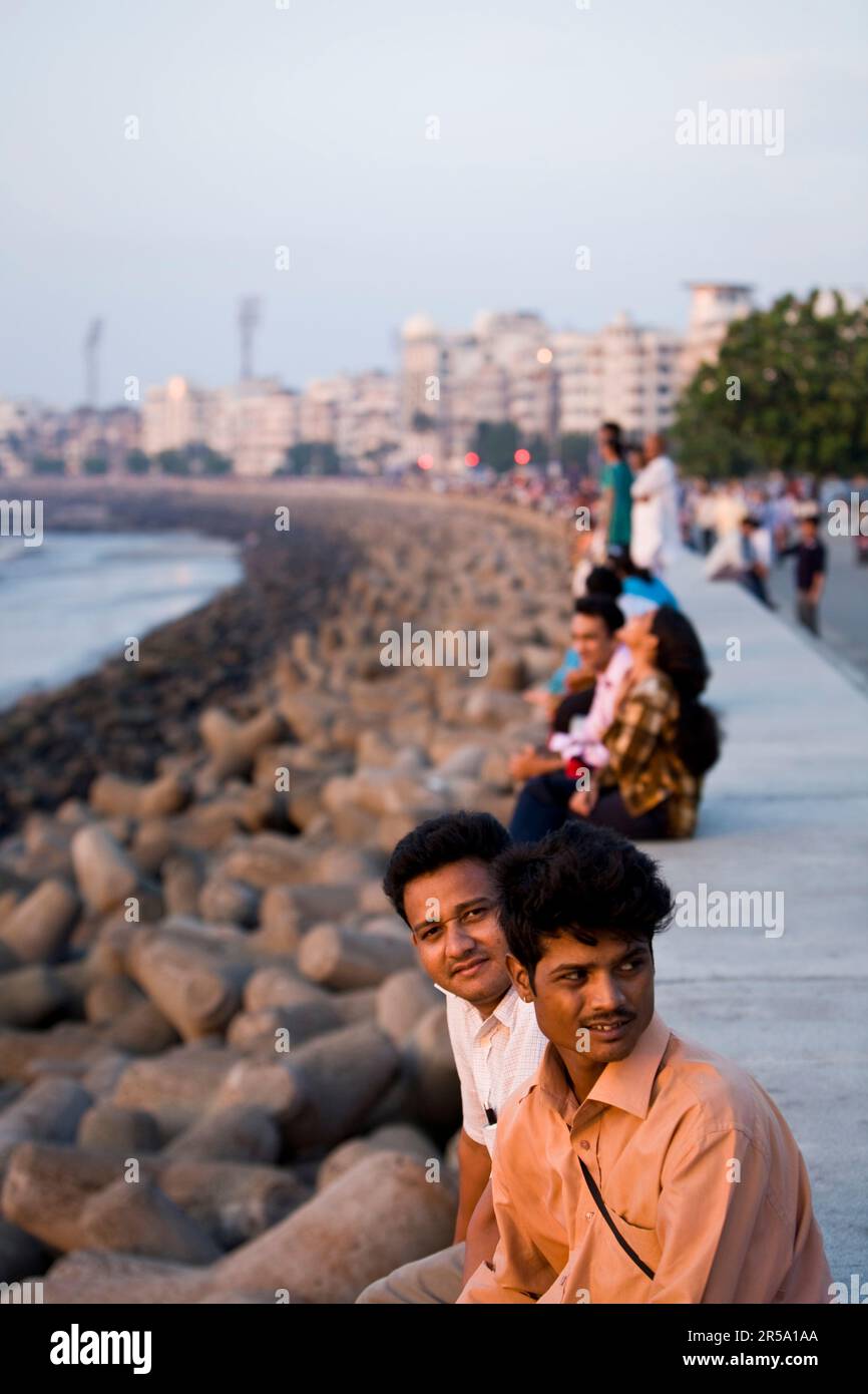 Les Indiens profitent du soleil couchant sur la mer d'Arabie le long du bord de mer de Marine Drive à Mumbai, en Inde. Banque D'Images