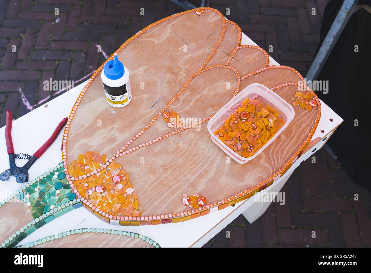 Atelier d'art recyclé dans la ville hollandaise - Hillegom. Vue en grand angle de la fleur de tulipe en bois décorée de morceaux de verre recyclé orange et vert. Personne. Photo de haute qualité Banque D'Images
