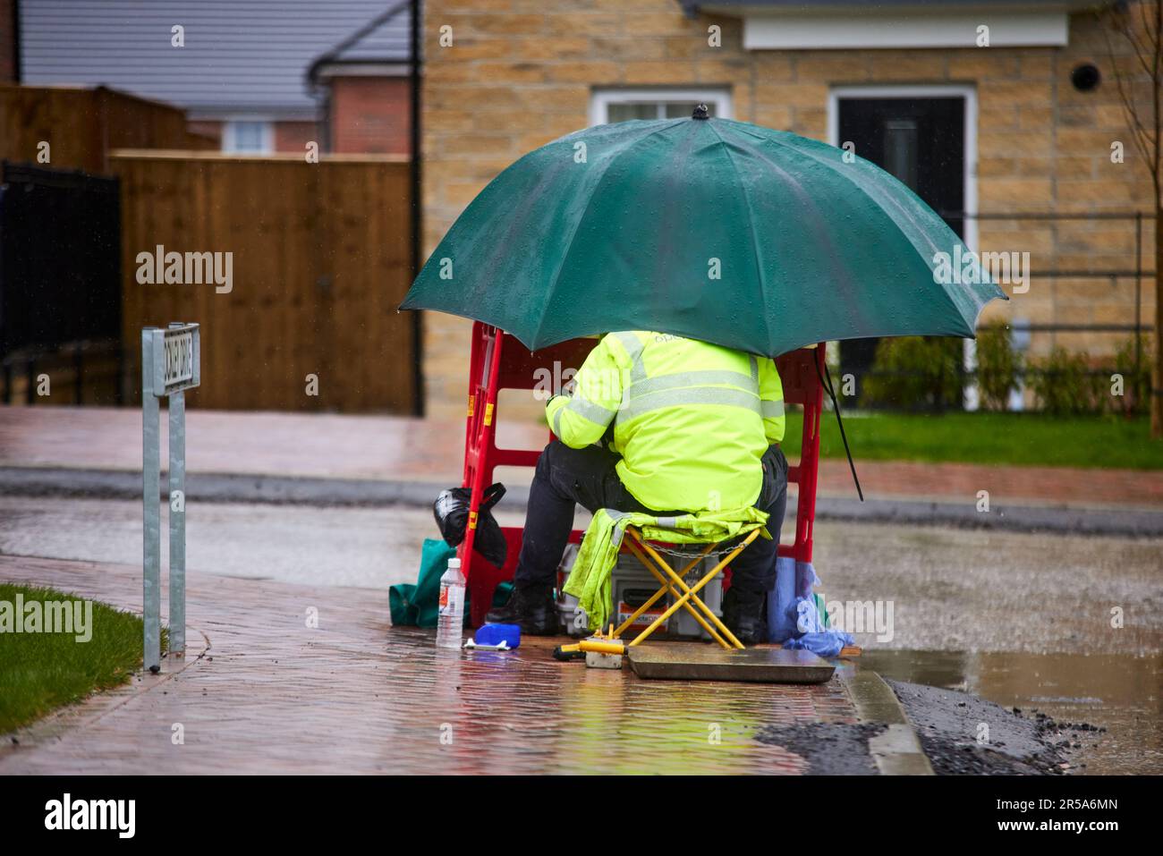 Temps humide BT OpenReach ingénieur connectant la bande haute vitesse travaillant sous la pluie Banque D'Images