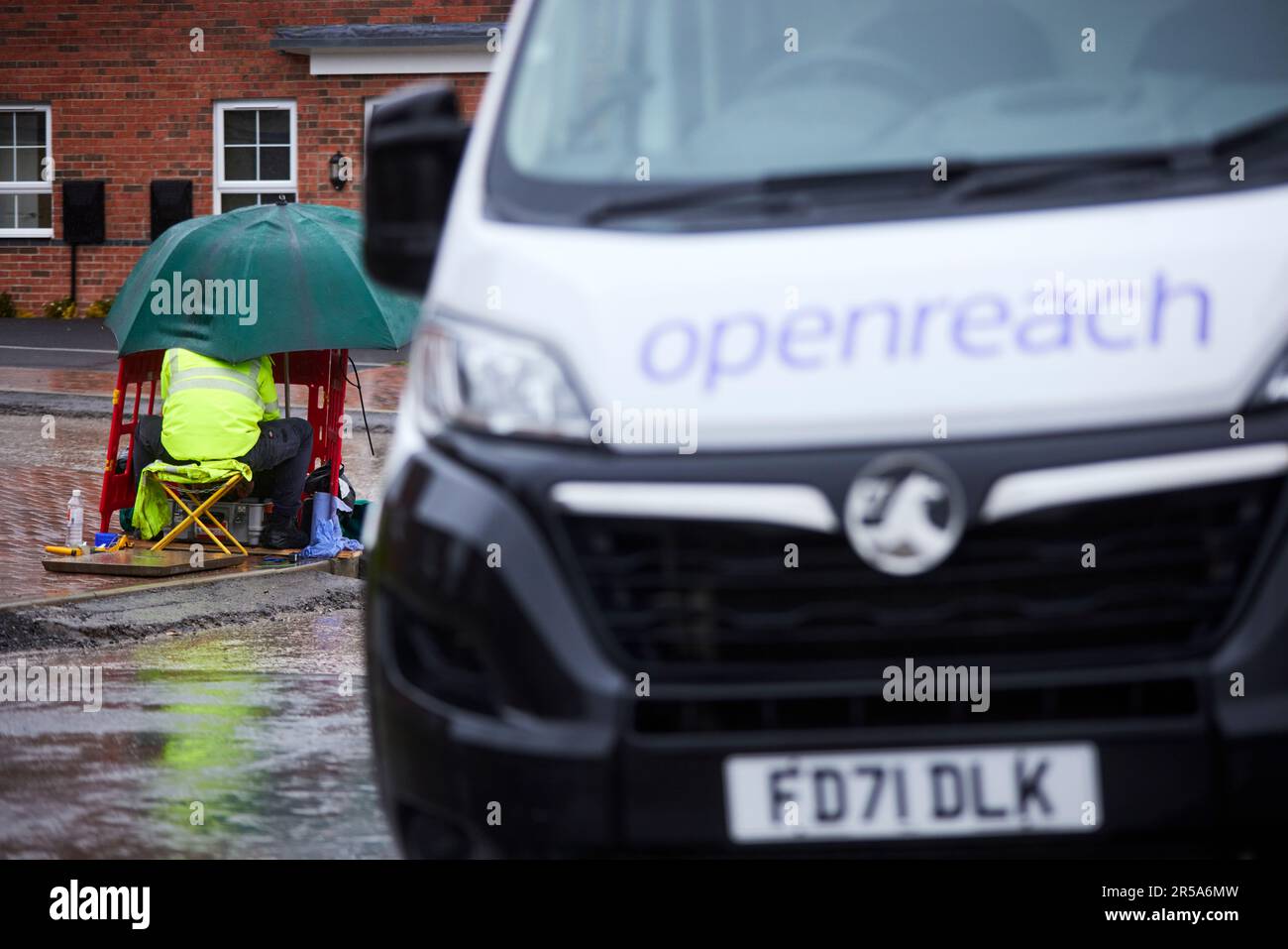 Temps humide BT OpenReach ingénieur connectant la bande haute vitesse travaillant sous la pluie Banque D'Images
