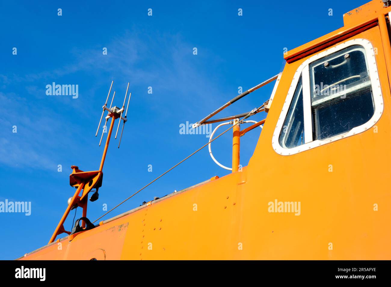 Mât de communication sur un canot de sauvetage orange vif ou un bateau de sauvetage contre un ciel bleu clair. Banque D'Images