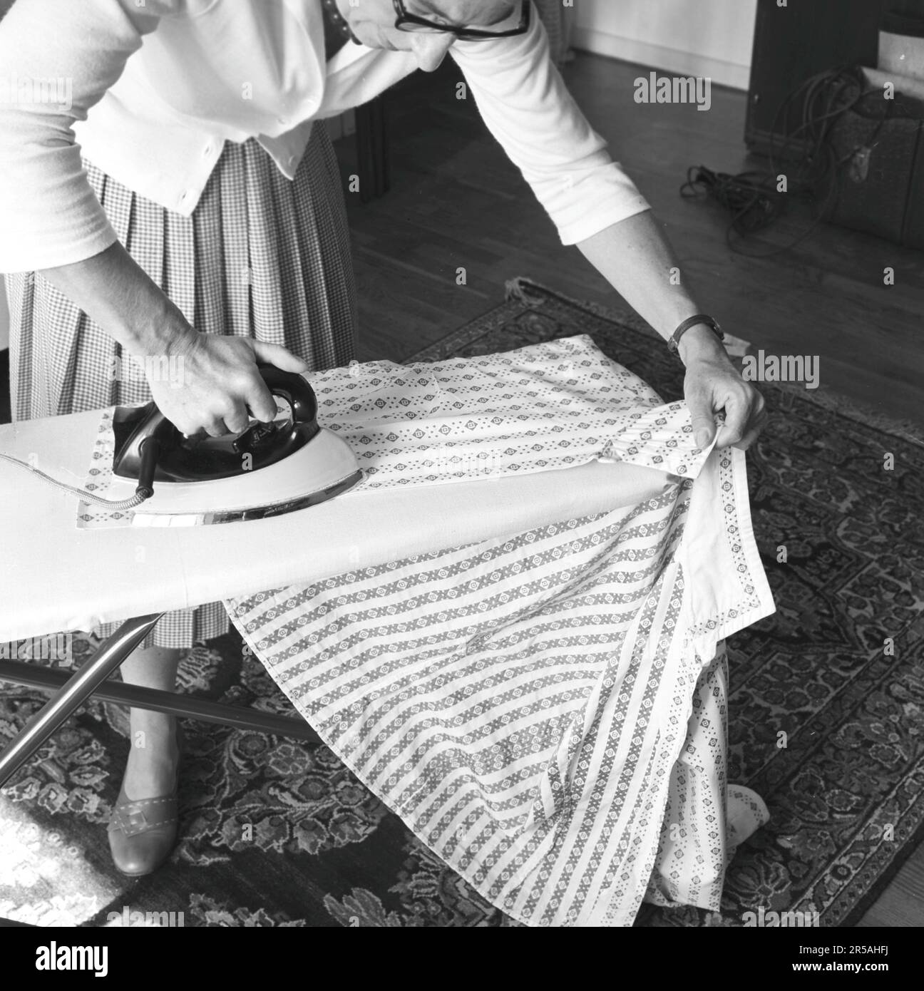 Repassage dans le 1950s. Une femme a vu repasser ses vêtements à la maison. Suède 1957 Banque D'Images