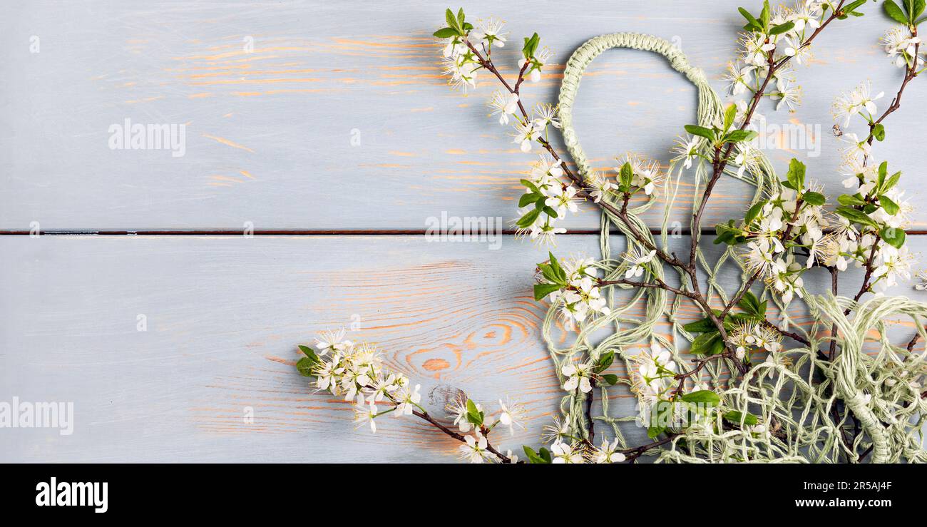 Sac à ficelle en filet vert avec branches en cerisier sur fond bleu en bois avec un emplacement pour votre texte. Plan d'agencement, vue de dessus. Aucun gaspillage et Banque D'Images