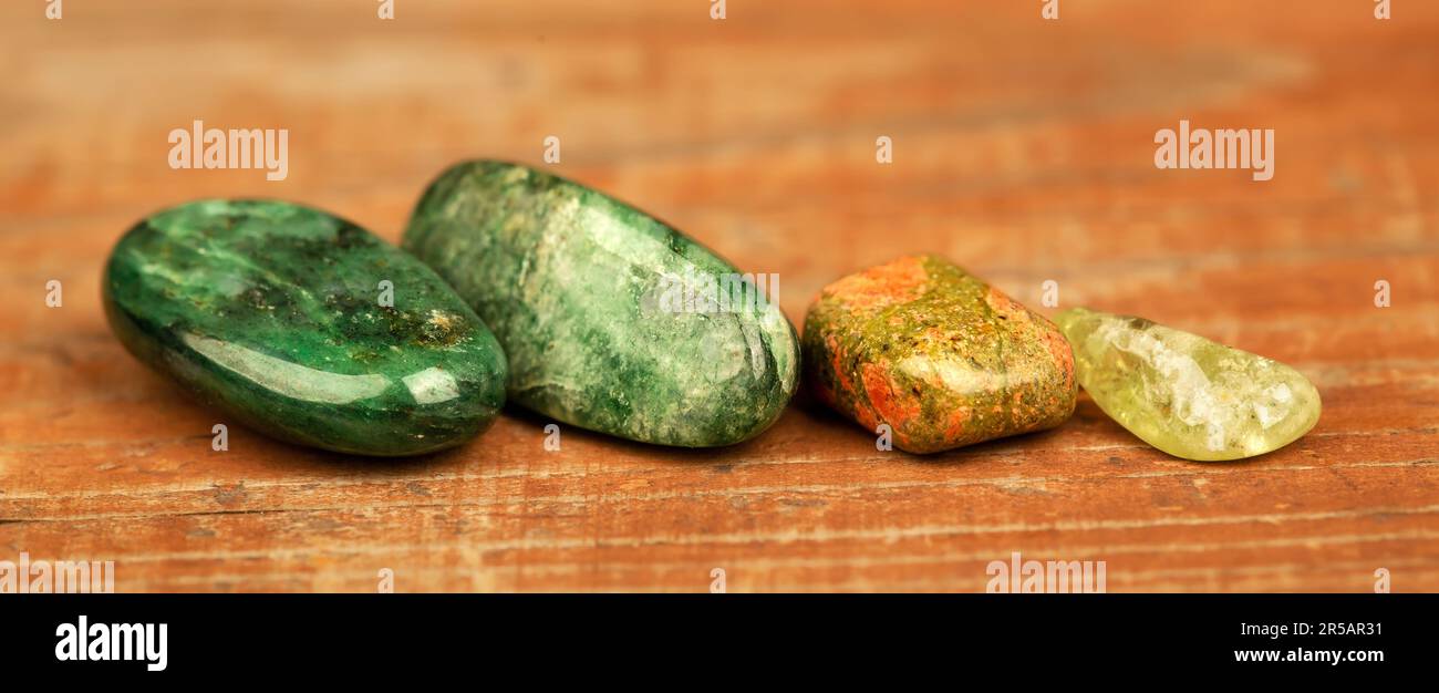 Pierres minérales vertes et jaunes sur un fond en bois. Banderole de bijoux en pierre précieuse de citrine, Aventurine, unakite. Banque D'Images