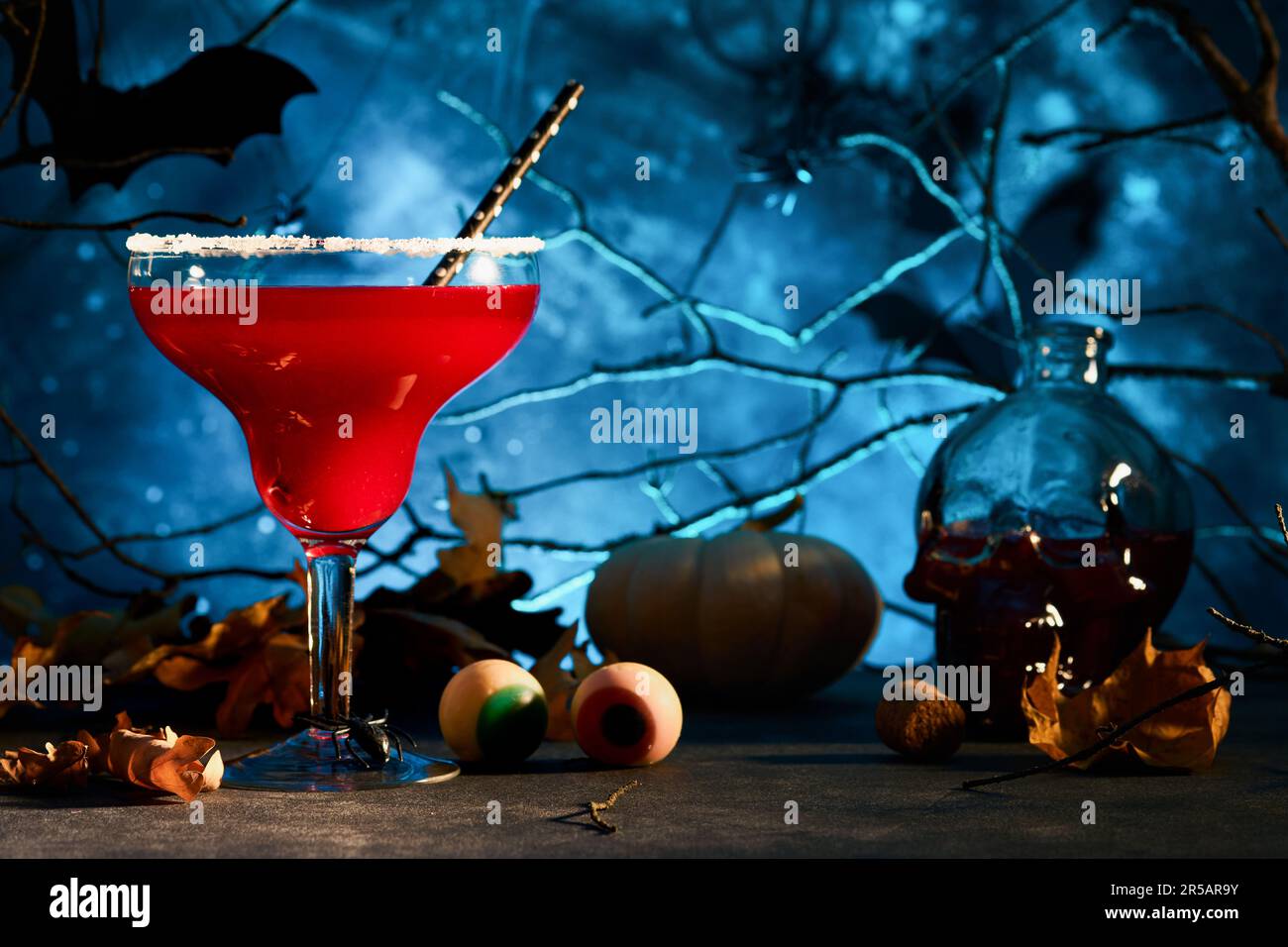 Halloween cocktail sanglant margarita. Cocktail rouge sanglant margarita et bouteille forment le crâne sur fond bleu sombre effrayant. Boisson de fête pour la fête avec Banque D'Images