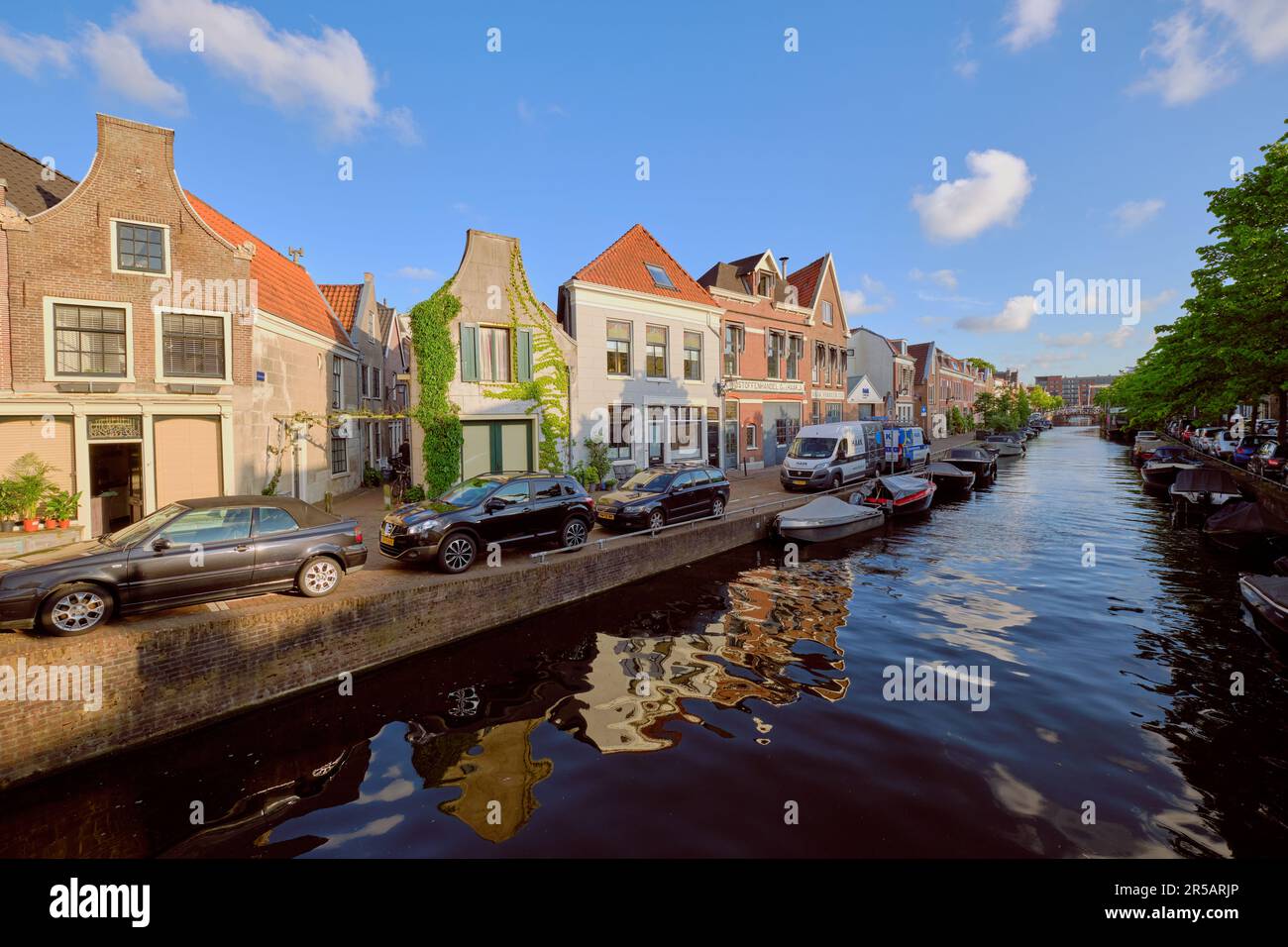 HAARLEM, PAYS-BAS - 24 MAI 2022 : réflexions claires des maisons en bordure de canal sur le canal de Burgwal lors d'une soirée ensoleillée. Banque D'Images