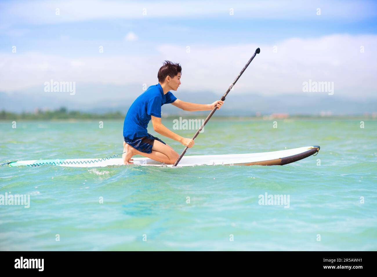 Enfant sur le paddle-board debout. Jeux aquatiques et sports de plage pour les enfants. Petit garçon sur planche à surf. Sports de plein air sains pour les vacances d'été Banque D'Images