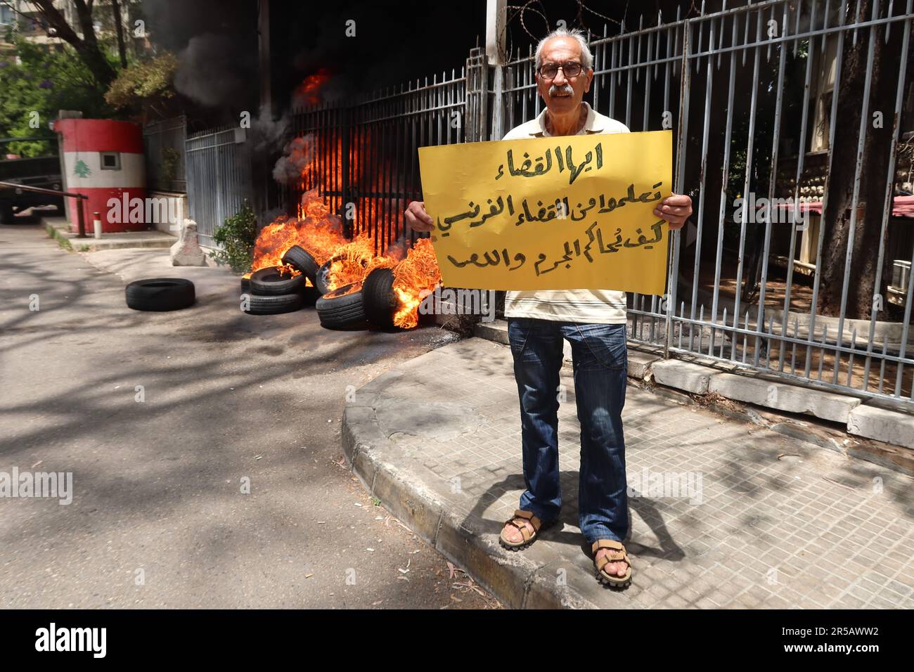 Un homme proteste contre le gouverneur de la Banque centrale libanaise Riad Salameh au Palais de Justice, Beyrouth, Liban, 1 juin 2023. L'affiche se lit comme suit : « les juges libanais apprennent de vos homologues français à poursuivre les criminels et les voleurs ». Le même jour, le Vice-Premier Ministre libanais Saade Chami a demandé la démission de Salameh après que le Gouvernement libanais ait reçu deux avis rouges d'Interpol pour lui. Selon des sources judiciaires, les avis faisaient suite à des mandats d’arrêt émis contre Salameh par des juges français et allemands pour des accusations de blanchiment d’argent, de fraude, de détournement de fonds et d’enrichissement illicite. Salame Banque D'Images