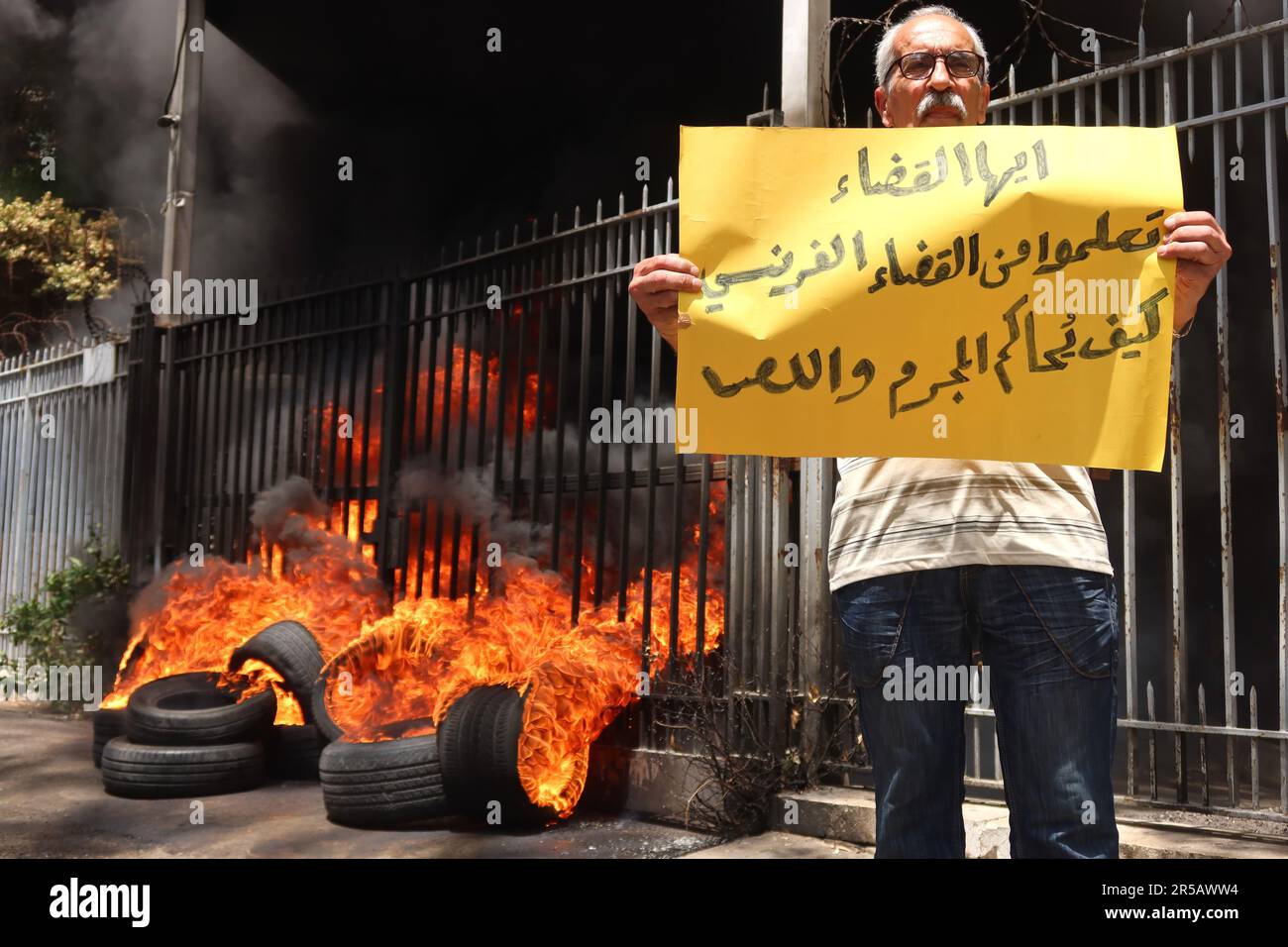 Un homme proteste contre le gouverneur de la Banque centrale libanaise Riad Salameh au Palais de Justice, Beyrouth, Liban, 1 juin 2023. L'affiche se lit comme suit : « les juges libanais apprennent de vos homologues français à poursuivre les criminels et les voleurs ». Le même jour, le Vice-Premier Ministre libanais Saade Chami a demandé la démission de Salameh après que le Gouvernement libanais ait reçu deux avis rouges d'Interpol pour lui. Selon des sources judiciaires, les avis faisaient suite à des mandats d’arrêt émis contre Salameh par des juges français et allemands pour des accusations de blanchiment d’argent, de fraude, de détournement de fonds et d’enrichissement illicite. Salame Banque D'Images