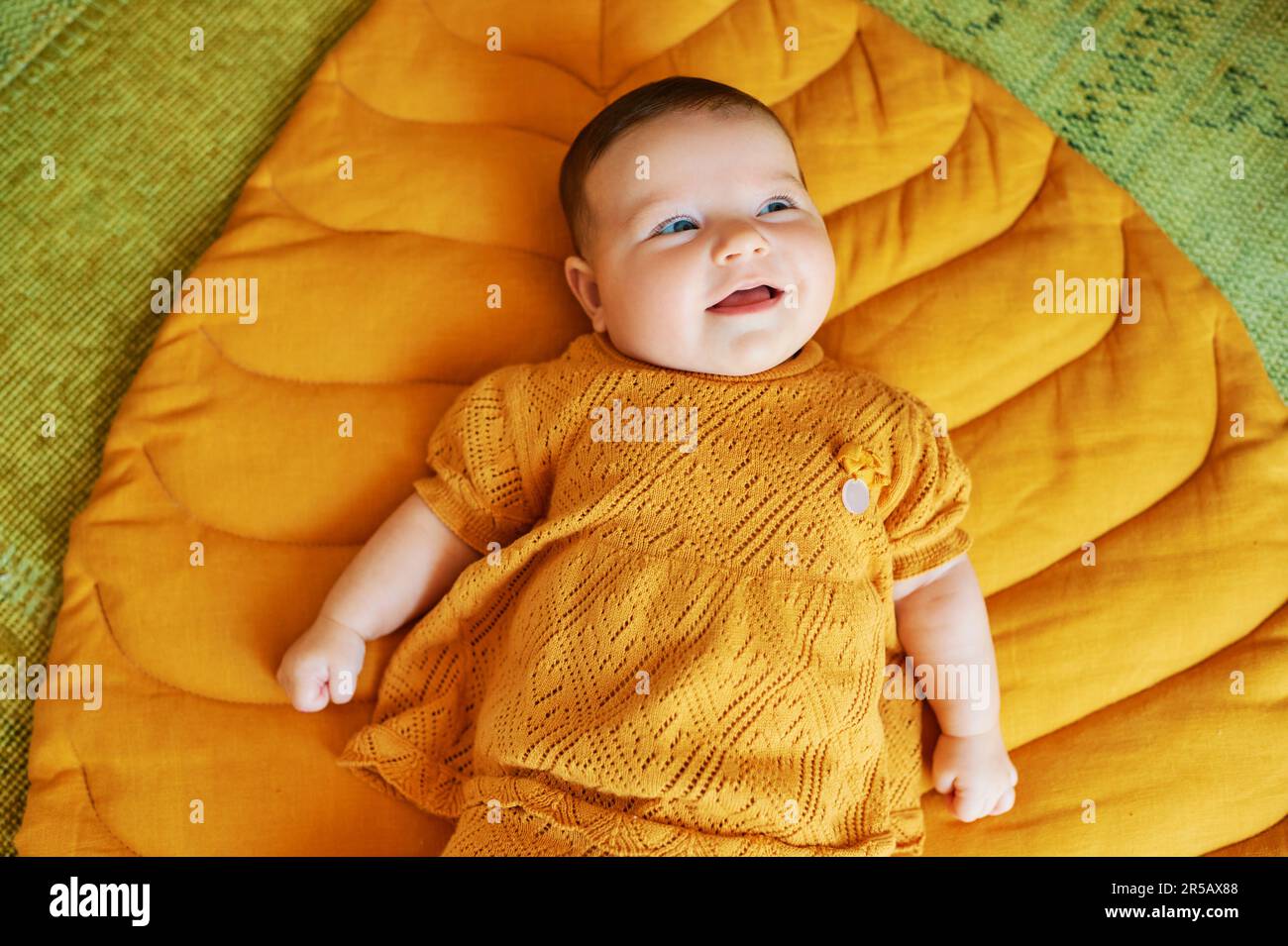 Portrait d'un adorable bébé de 6 mois allongé sur une couverture de jeu jaune Banque D'Images