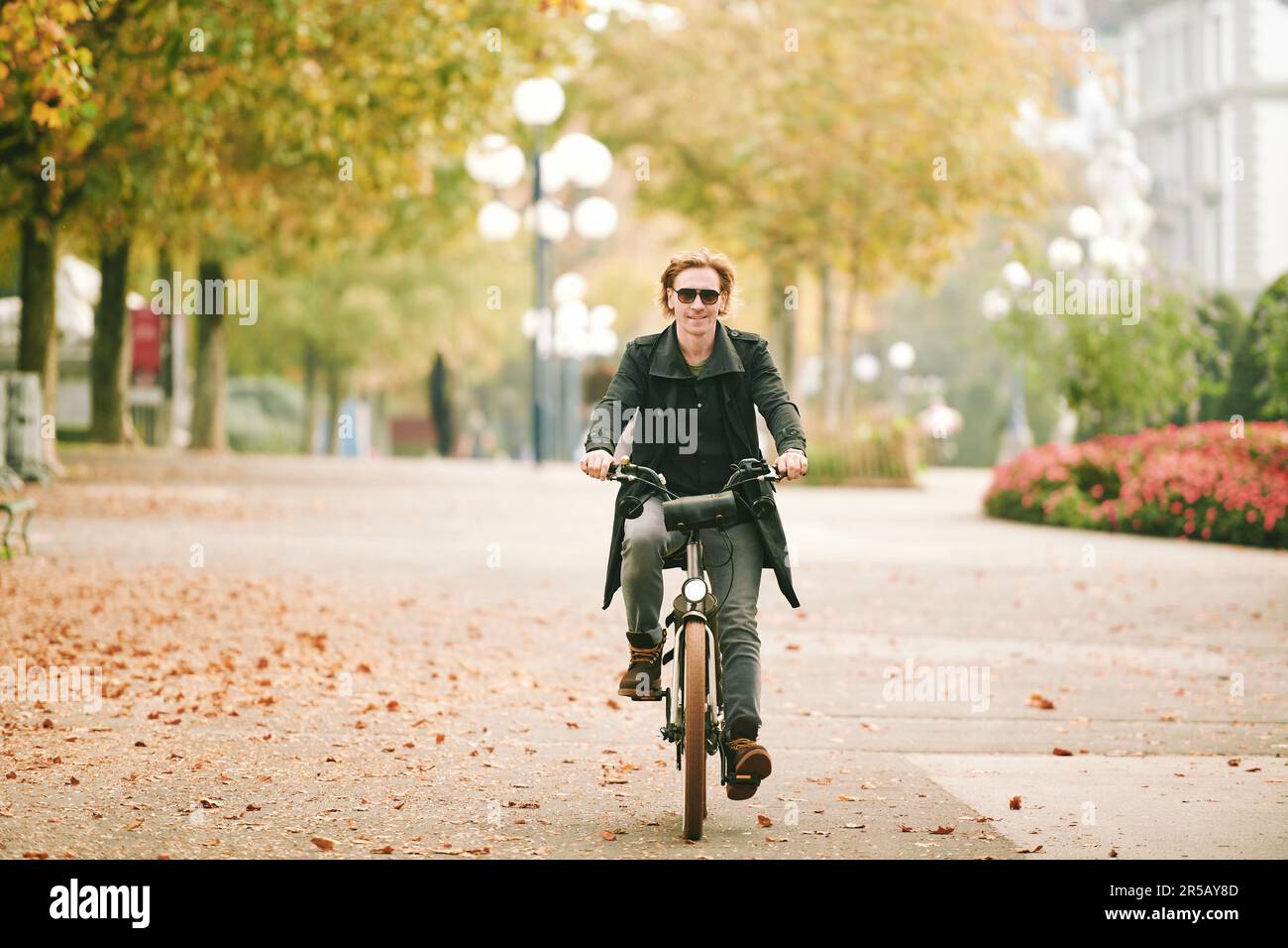 Portrait en plein air d'un beau homme à cheveux lus qui fait du vélo dans une ville Banque D'Images